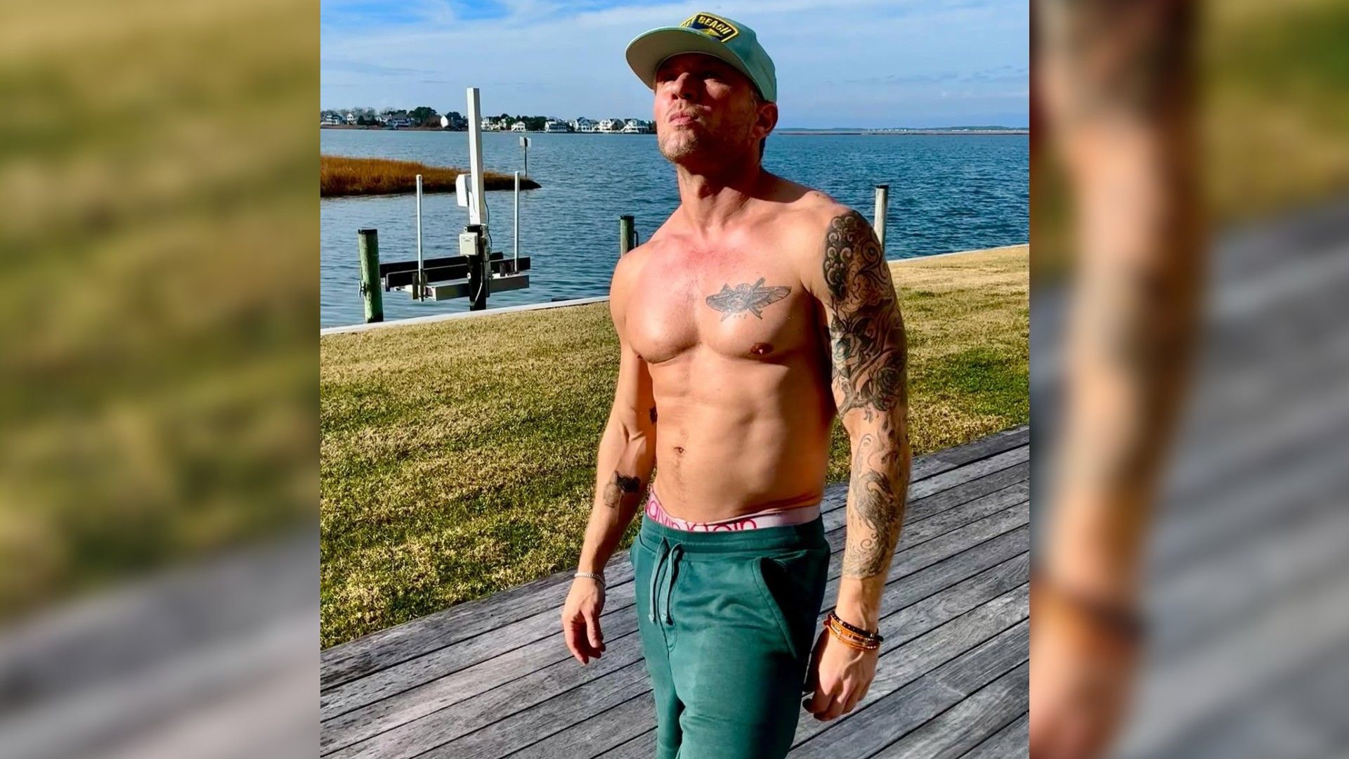 An athletically built middle-aged man without a T-shirt is standing on the pier