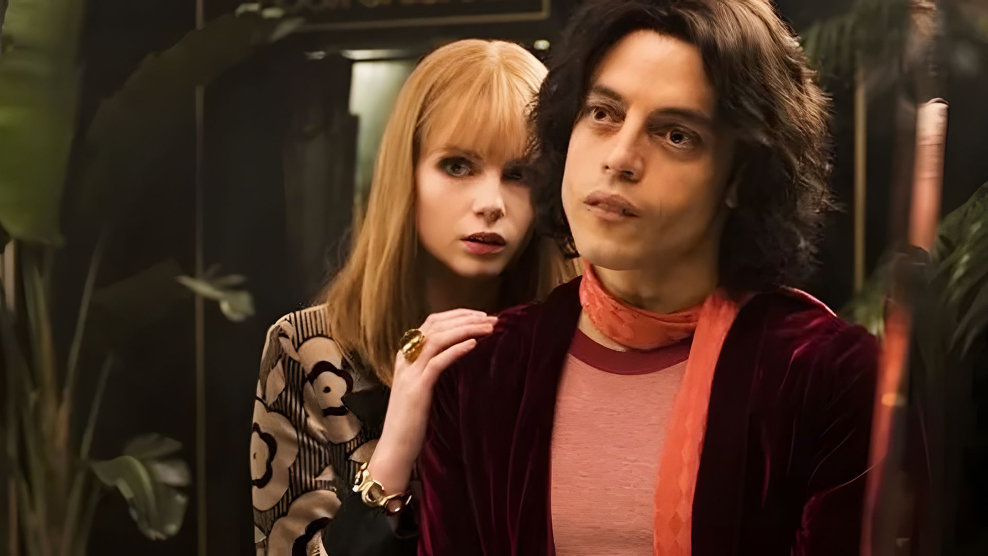 A man and woman in 70s-era suits stand by the mirror