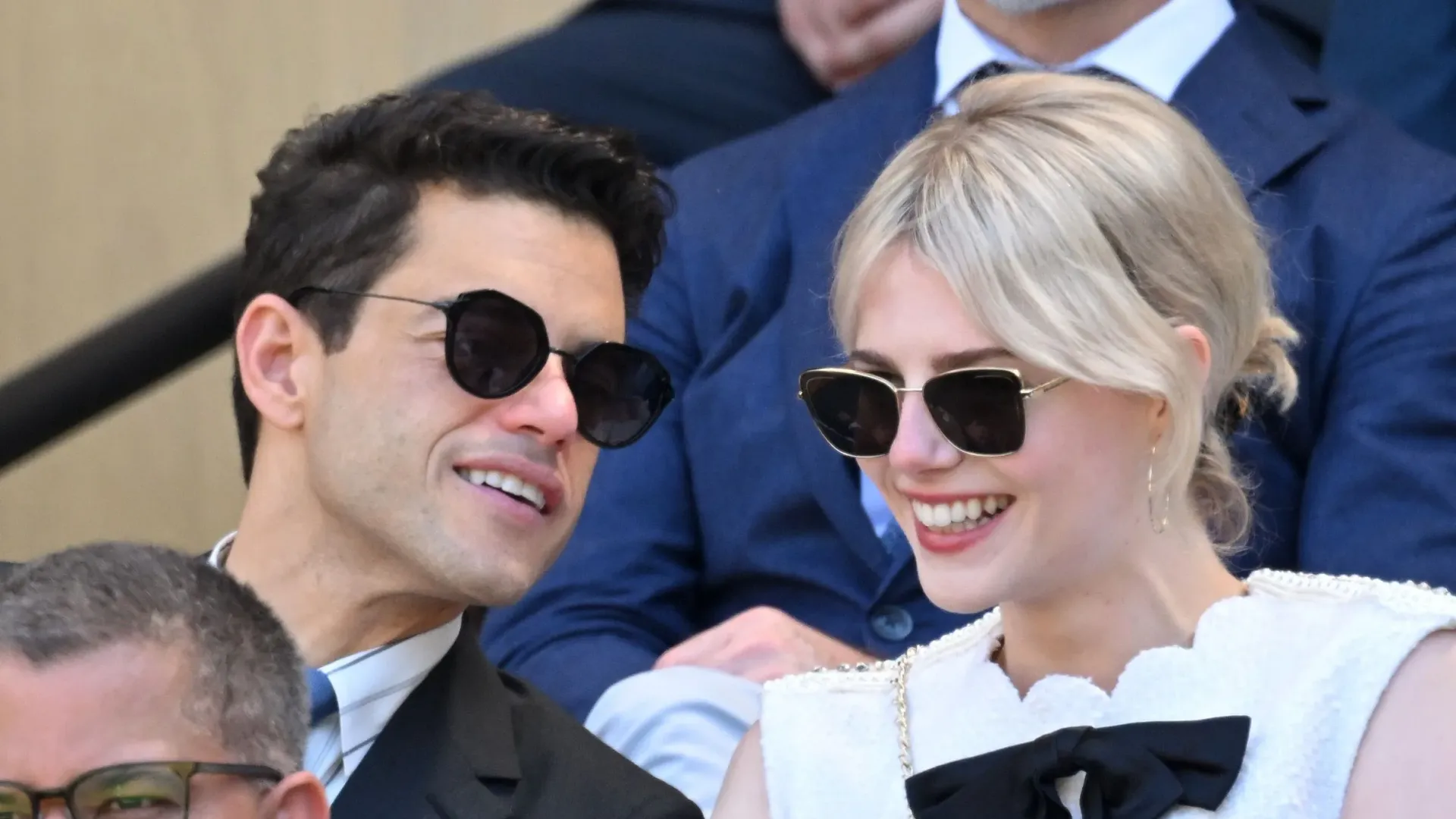 A man and woman in sunglasses are sitting in the stands of the stadium