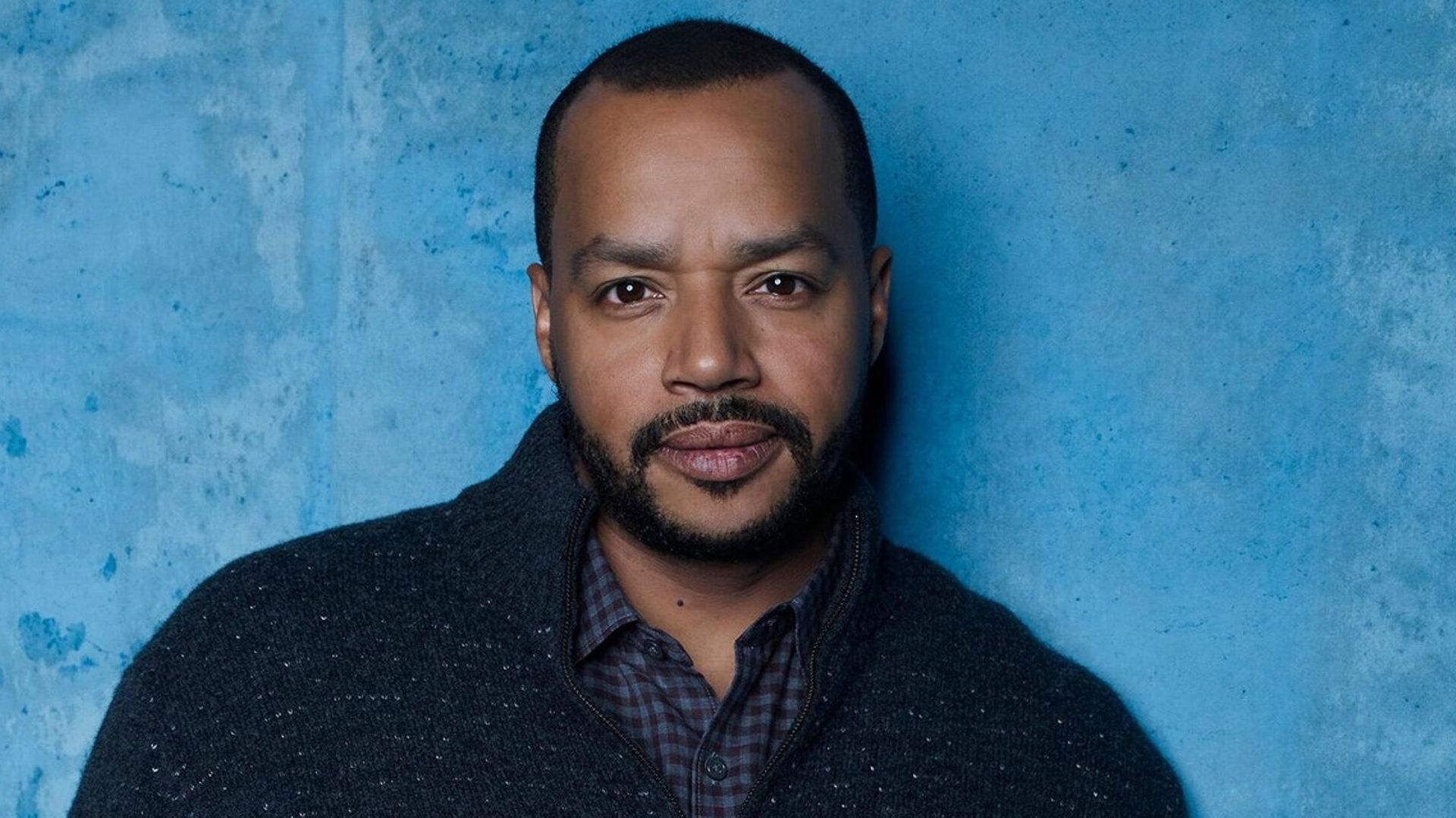 Actor Donald Faison in a blue sweater against a light blue background
