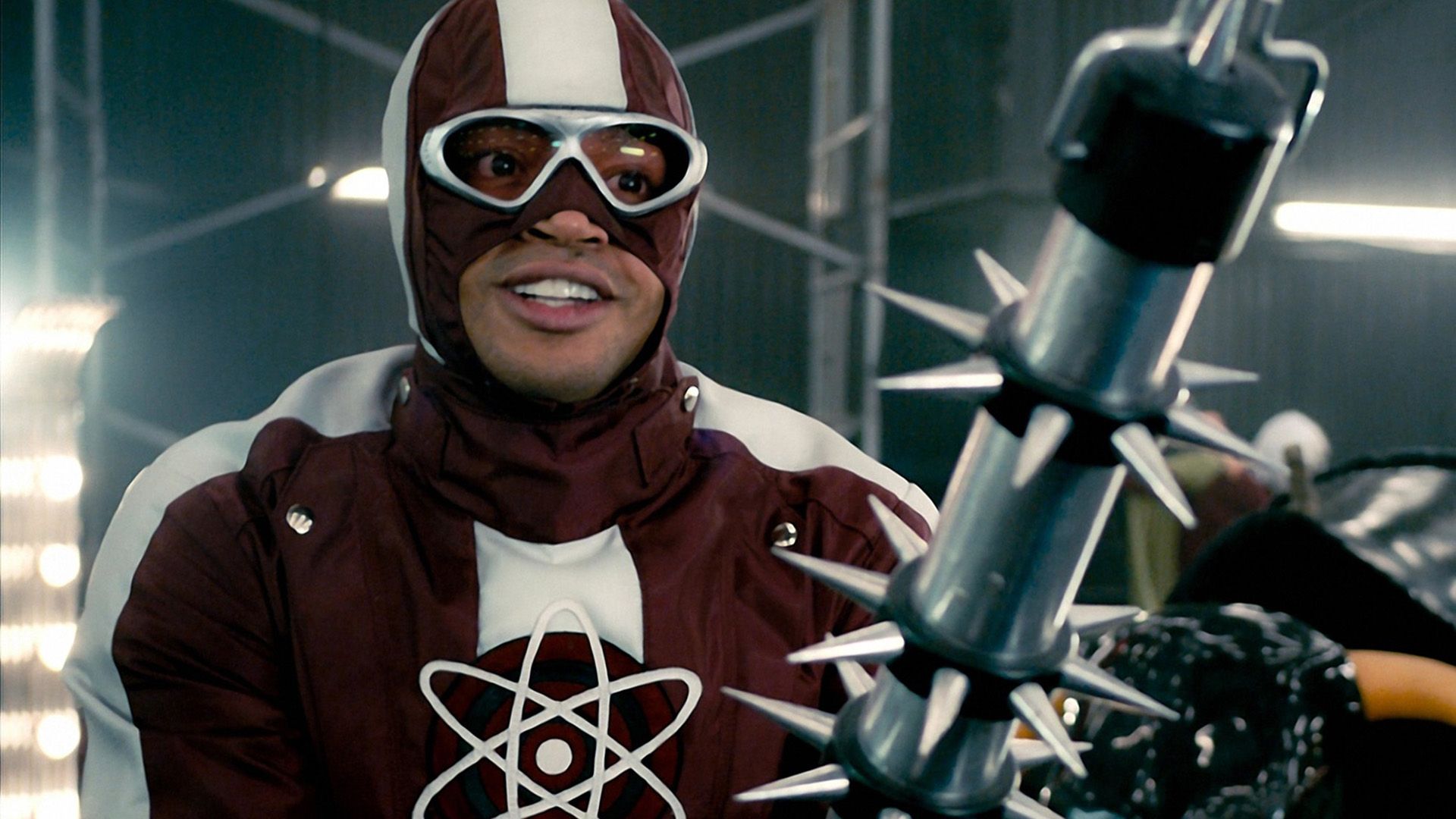 Donald Faison in a red and white jacket and mask covering half his face