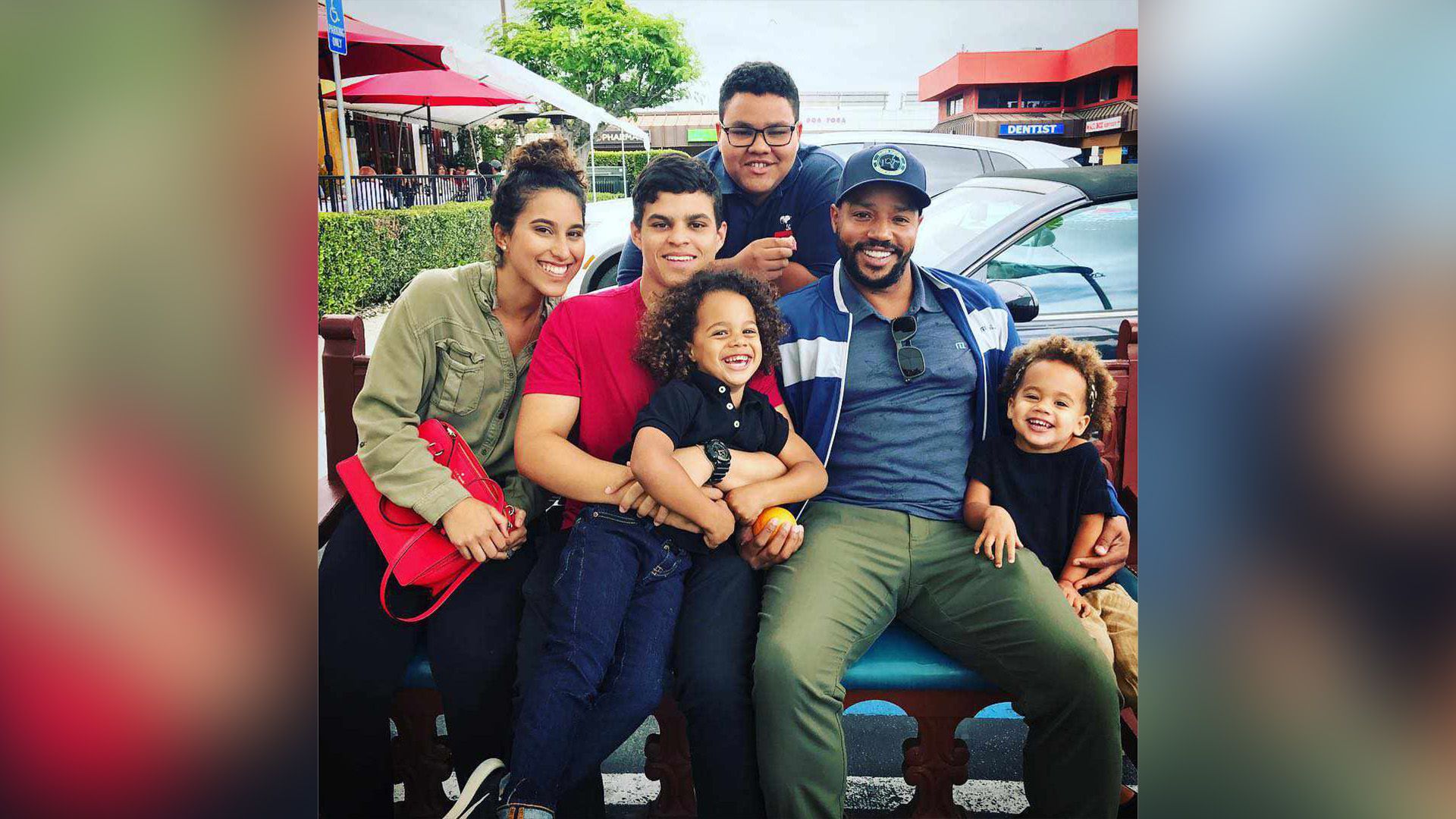 Happy Donald Faison sits in the yard surrounded by his children