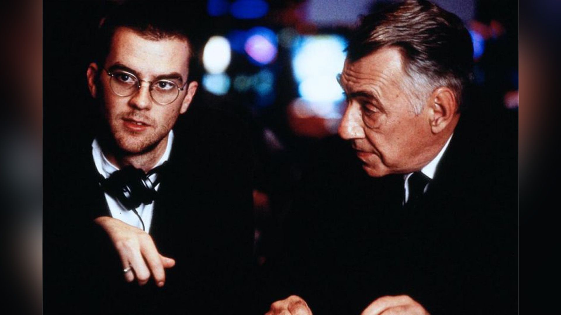 Paul Thomas Anderson wearing glasses with headphones around his neck and Philip Baker Hall