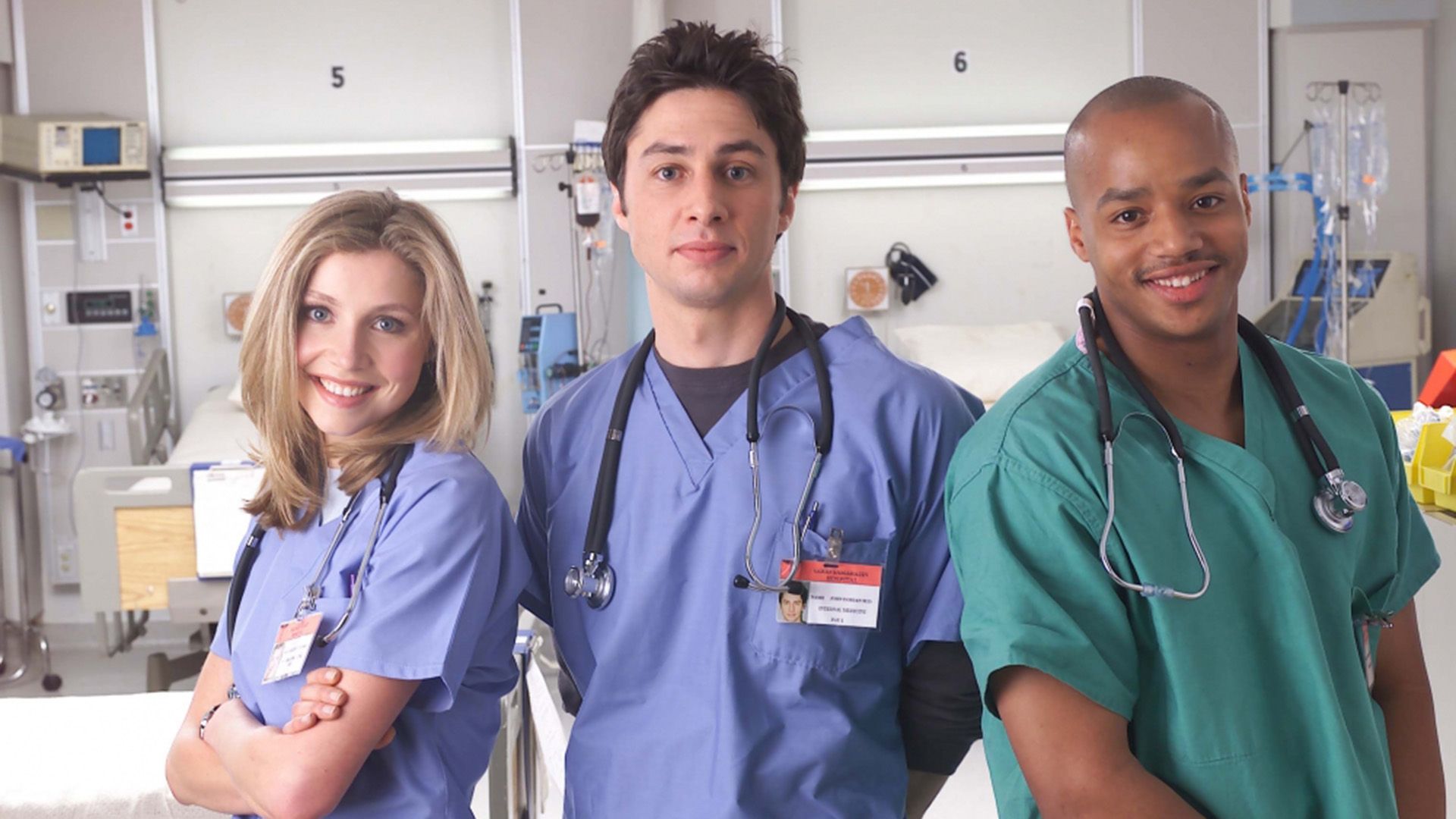 Sarah Chalke, Zach Braff, and Donald Faison in medical scrubs standing in a hospital room and smiling