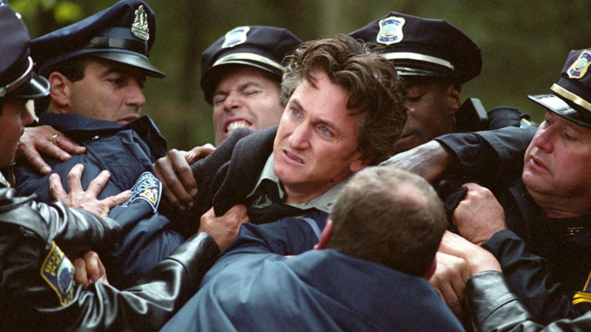 An enraged Sean Penn being restrained by five uniformed police officers