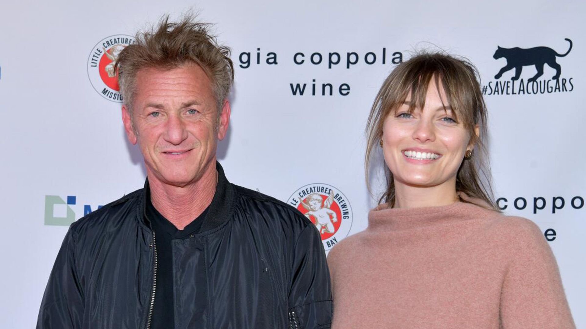 Sean Penn in a black jacket and Leila George in a beige sweater