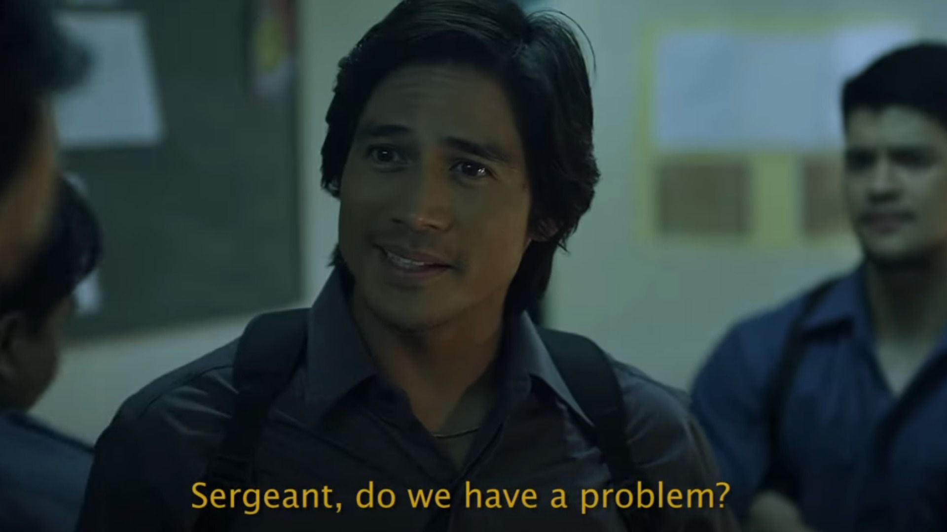 A man in a gray shirt looks questioningly to the side
