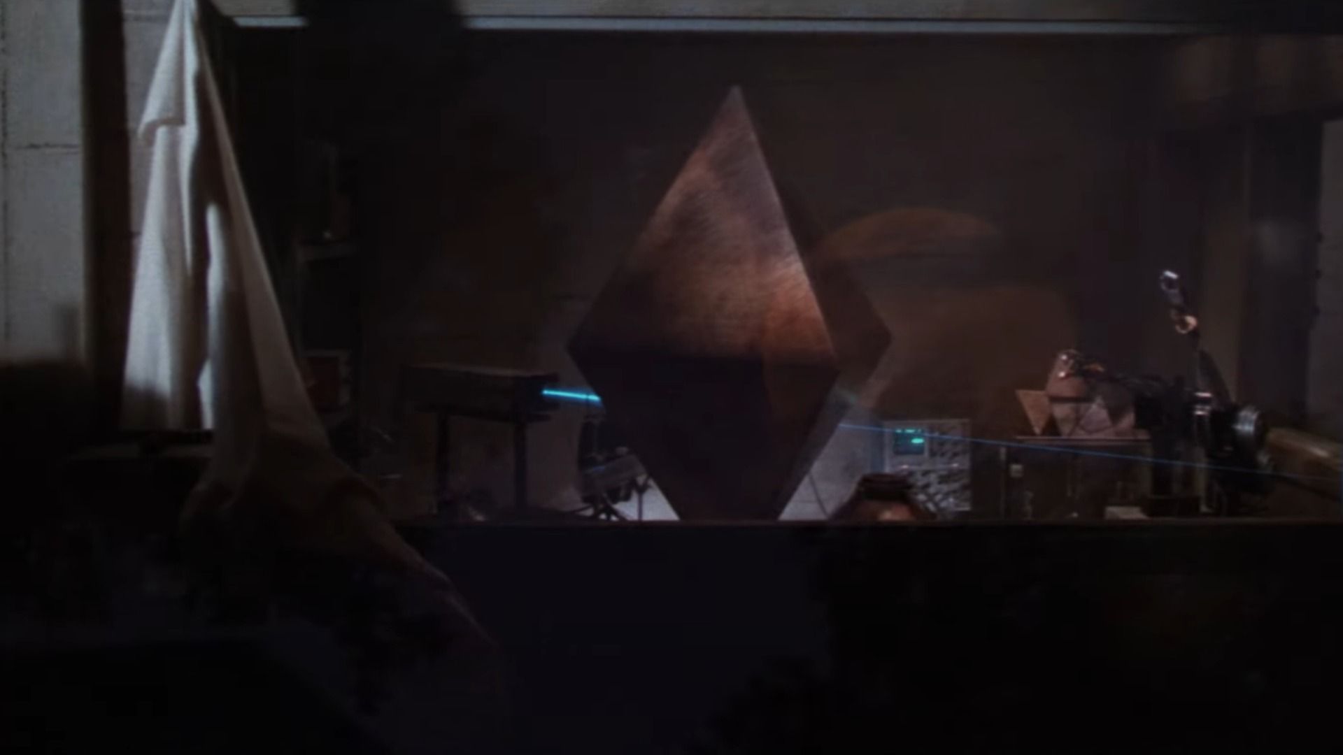 A metal diamond standing in the middle of a dark room