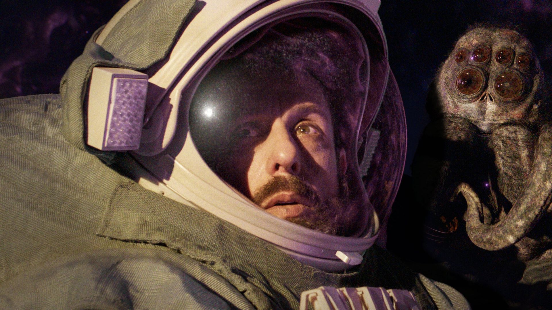 Adam Sandler in an astronaut helmet, with a giant insect on the right