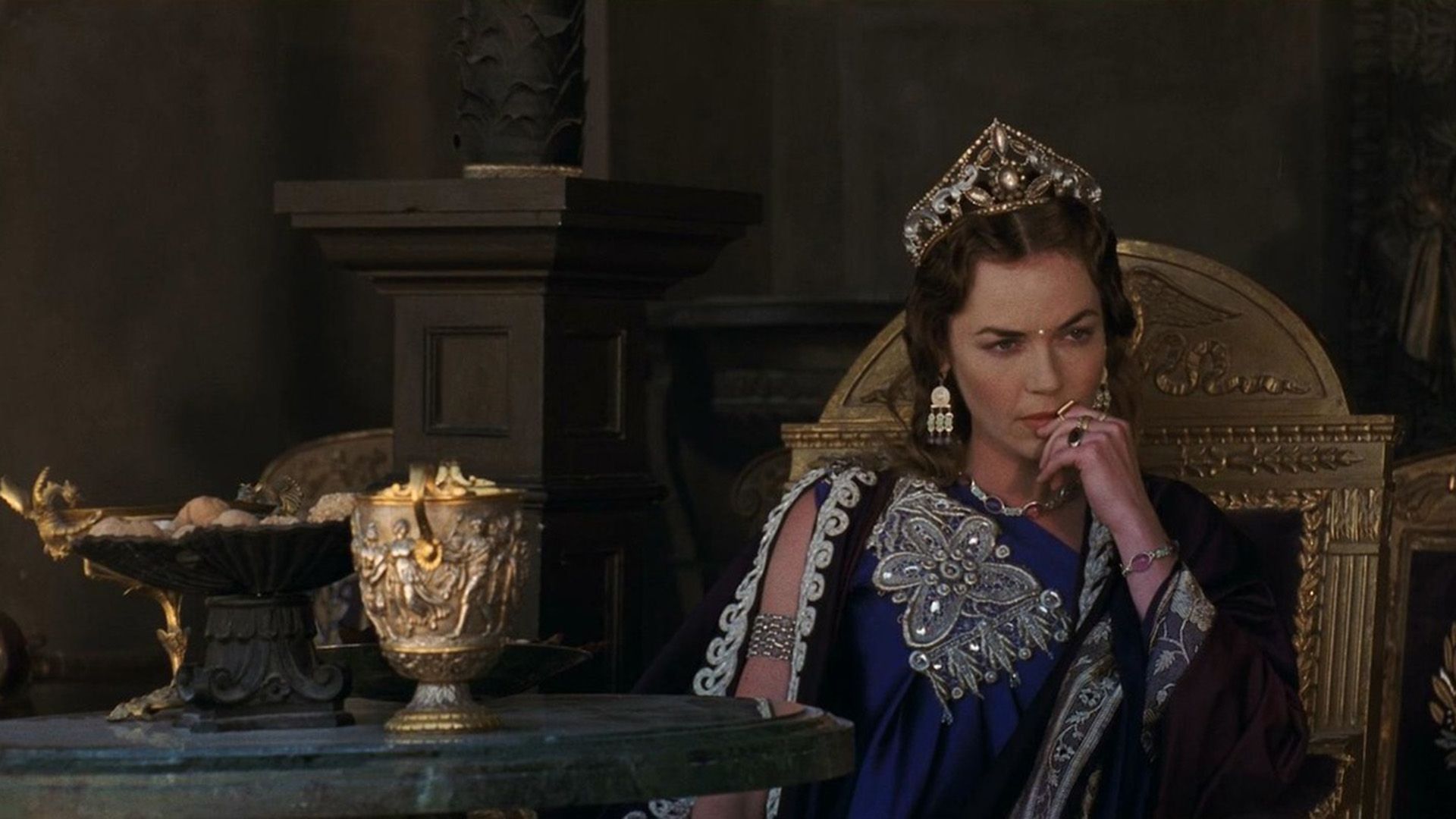 Connie Nielsen as Lucilla sits pensively on a golden throne