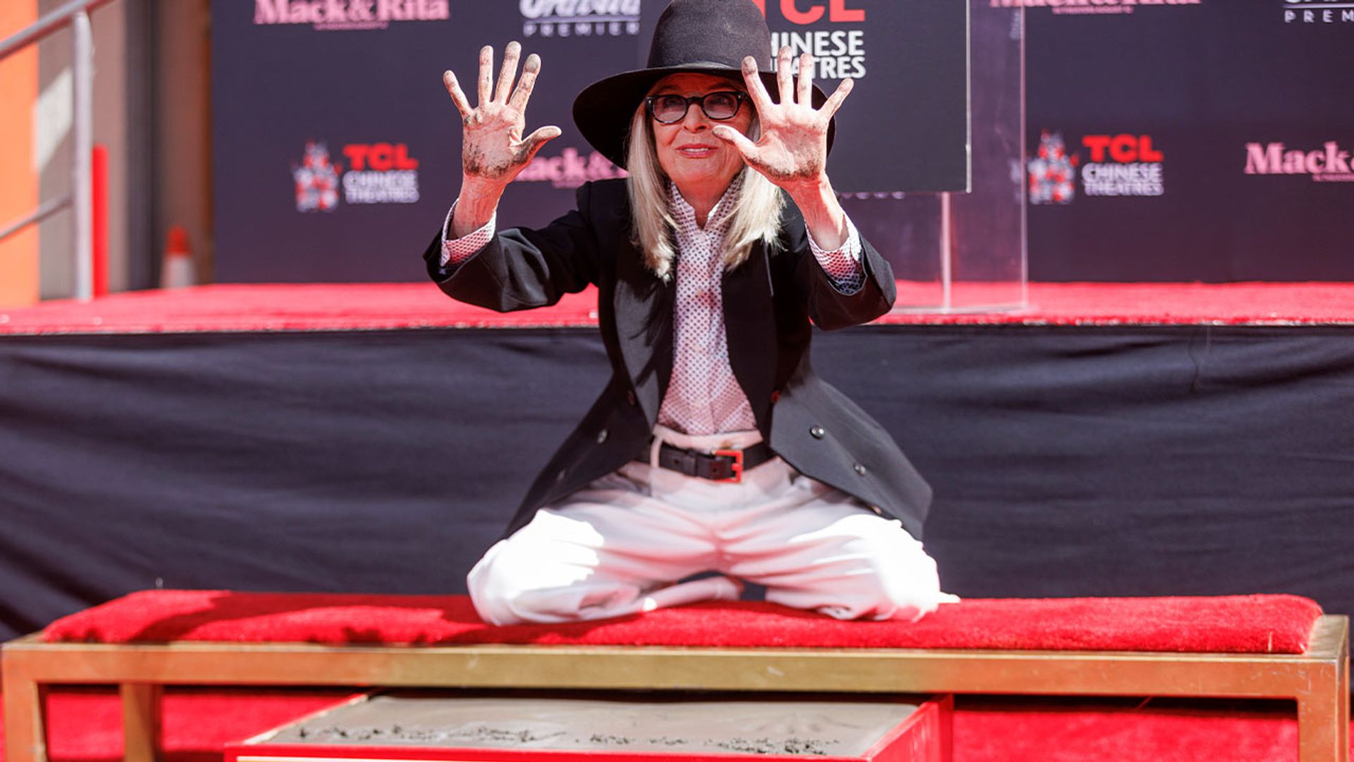 Diane Keaton in a hat and pantsuit leaves her handprints in concrete