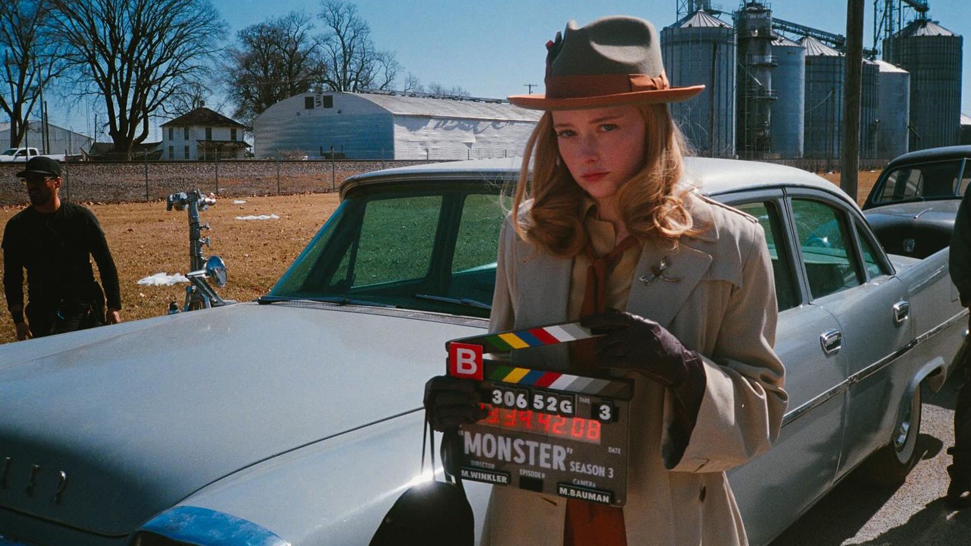 Suzanna Son in early 20th century fashion holds a clapperboard labeled Monster