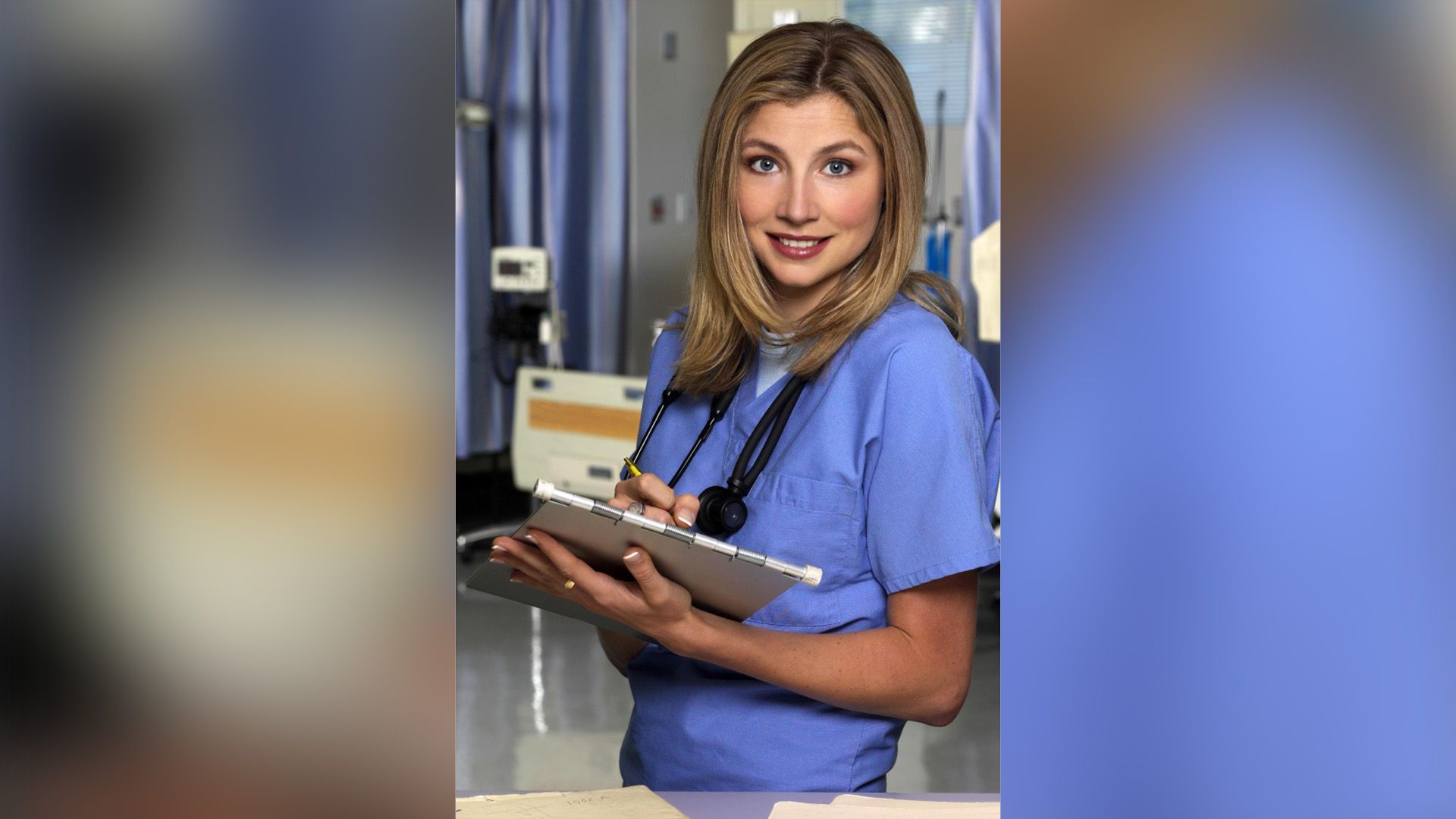 Sarah Chalke in doctor's scrubs with a clipboard in her hands