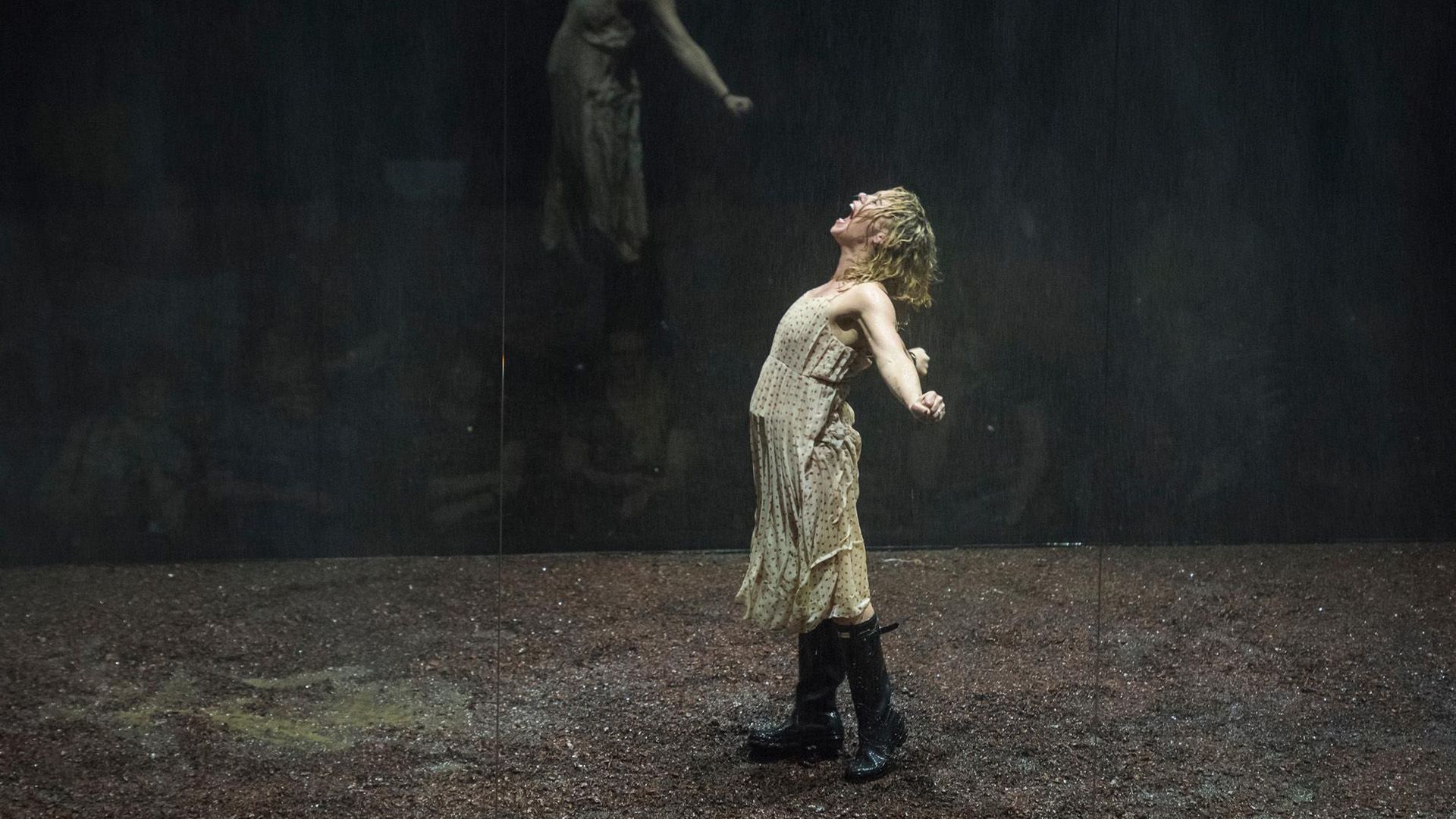 Billie Piper in a light dress and high boots stands on stage, arms outstretched, screaming