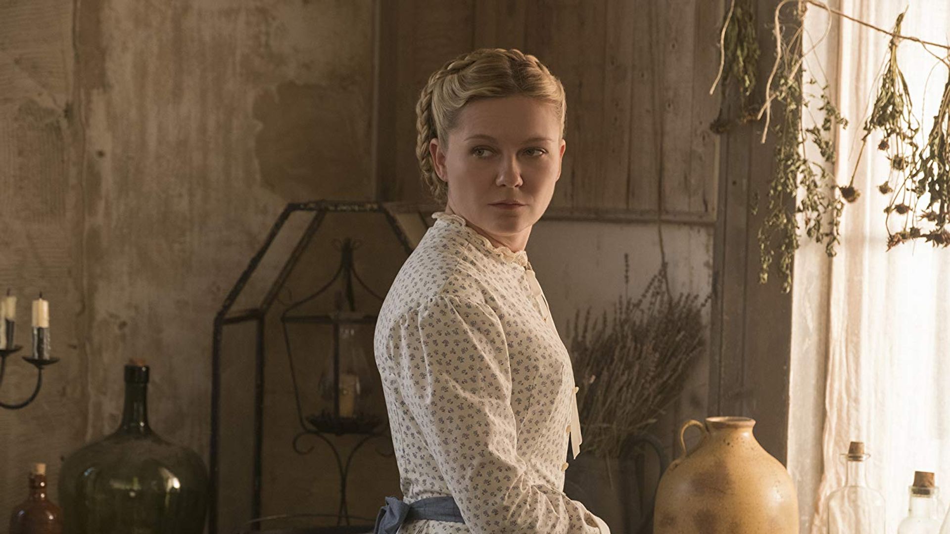 Kirsten Dunst in a vintage white dress stands at a three-quarter angle