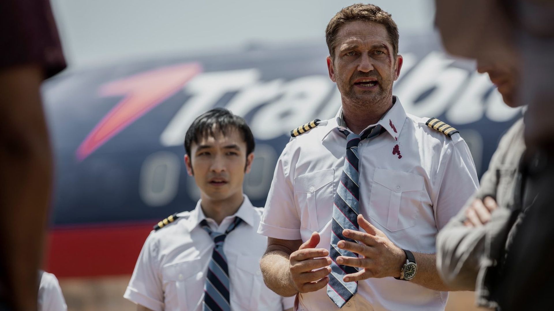 Gerard Butler in pilot uniform against an airplane backdrop, scene from the film