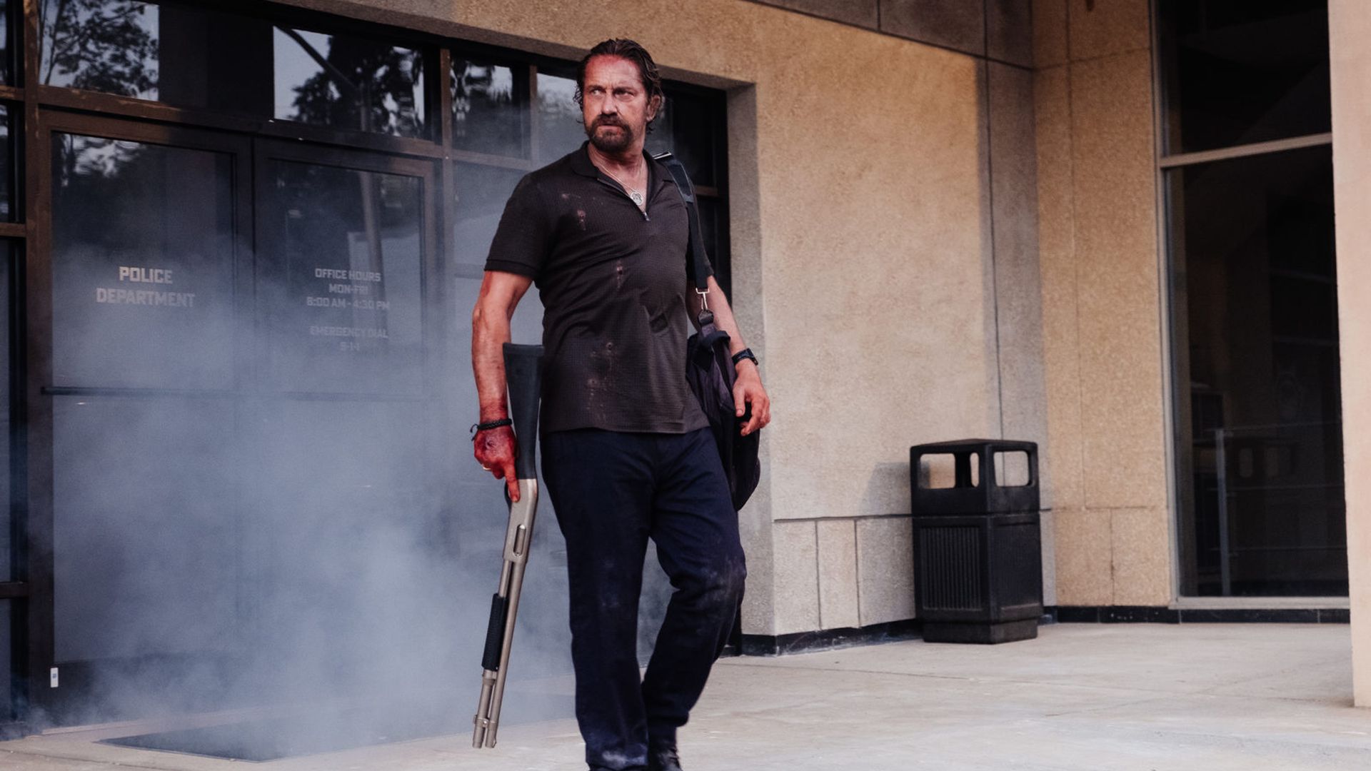 Gerard Butler standing full height holding a weapon, scene from the film
