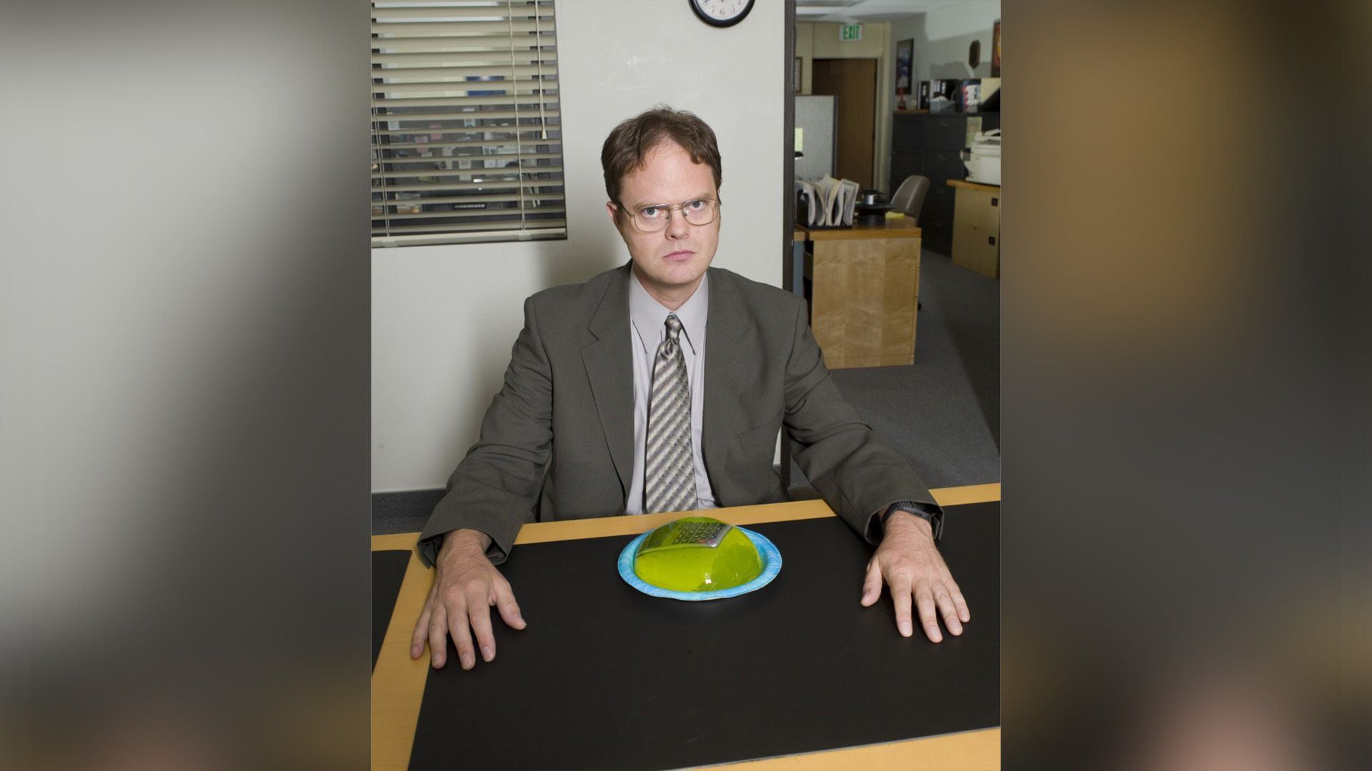 Rainn Wilson sits at a table with a plate in front of him containing a calculator covered in green Jell-O