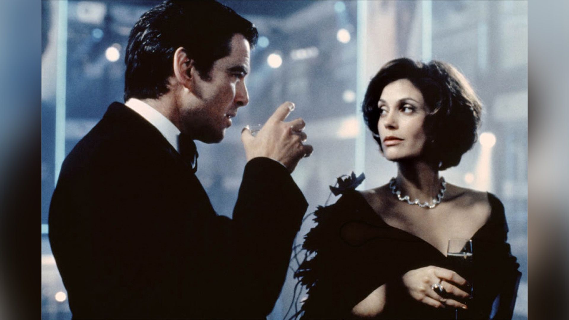 Teri Hatcher in an evening gown and diamond necklace holds a glass with a man in a tuxedo standing beside her