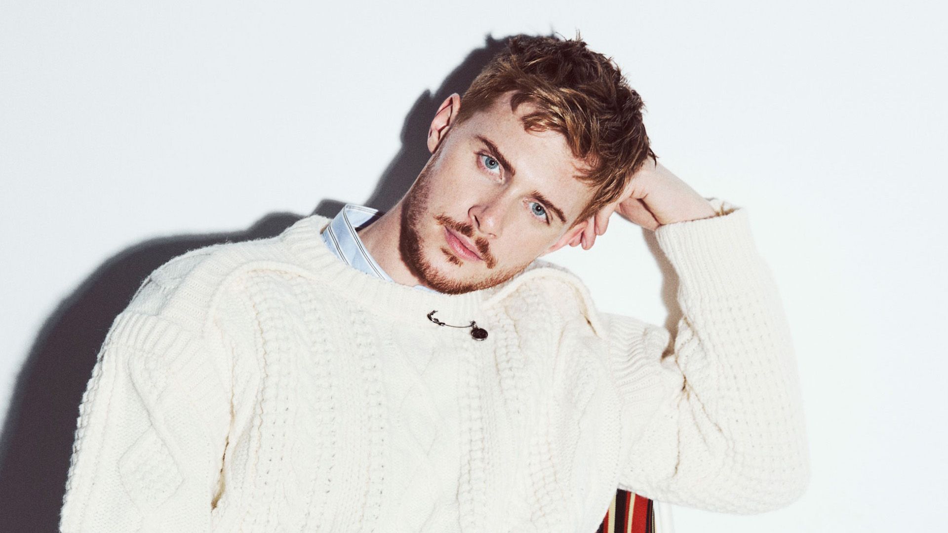 Actor Max Parker in a white knit sweater against a light background