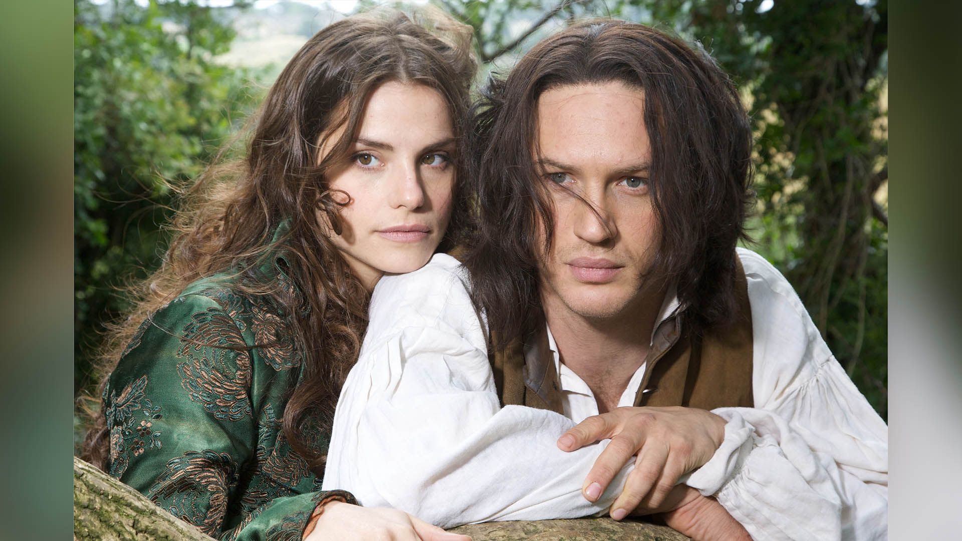 Charlotte Riley in a green dress and Tom Hardy in a white shirt with long hair