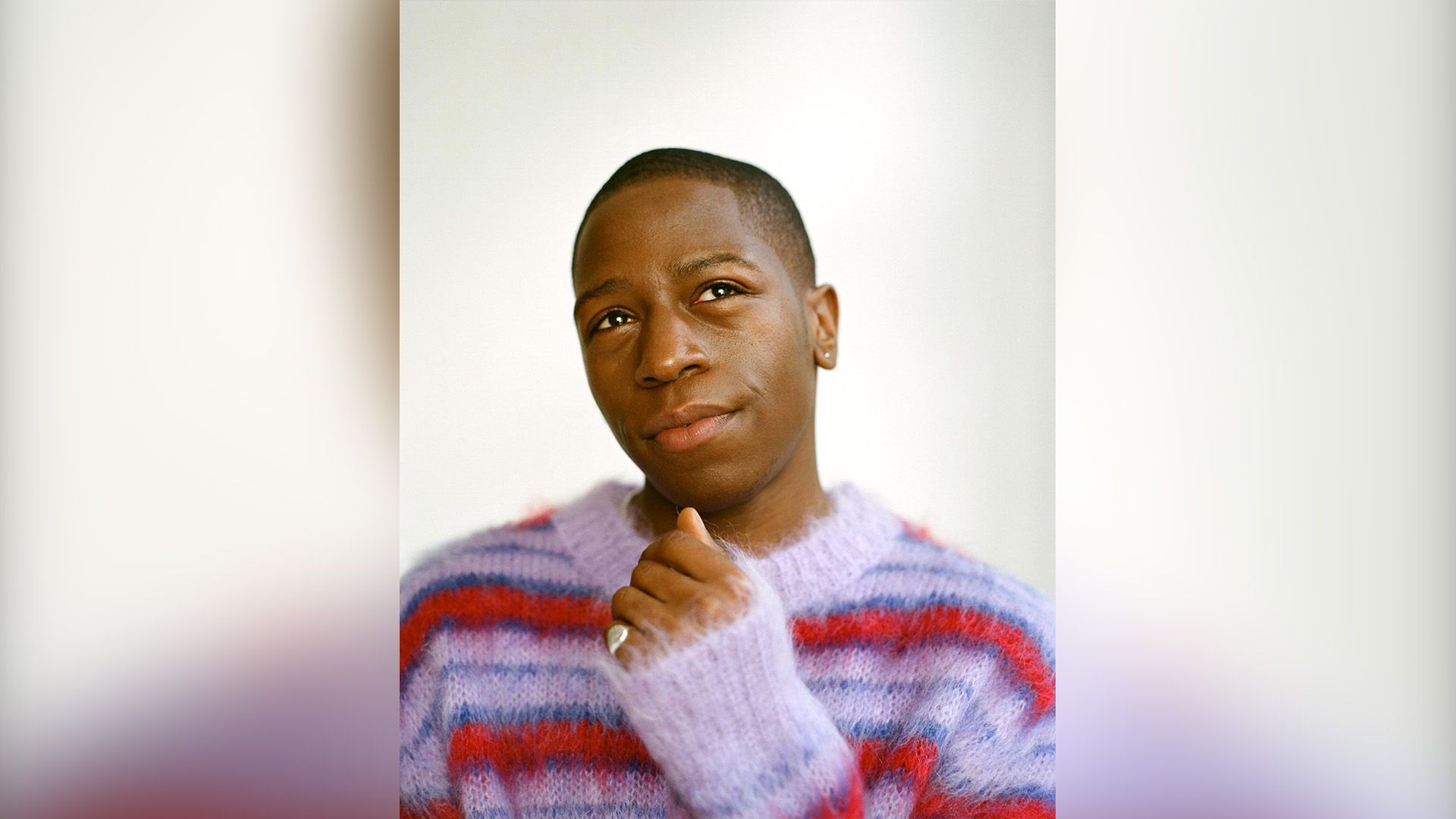 David Jonsson in a fluffy red and purple striped sweater gazes dreamily upward