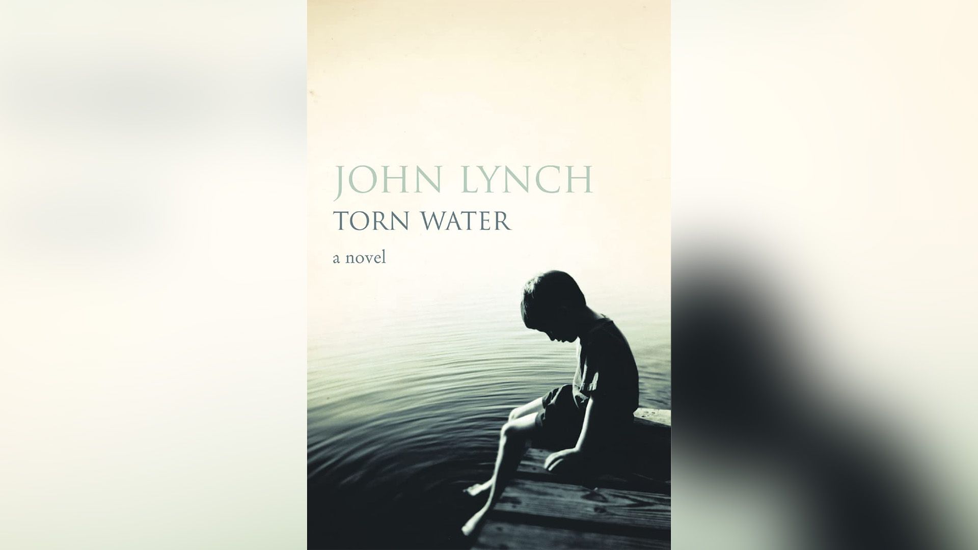 Book cover for "Torn Water": a boy sitting on a pier with his legs dangling in the water