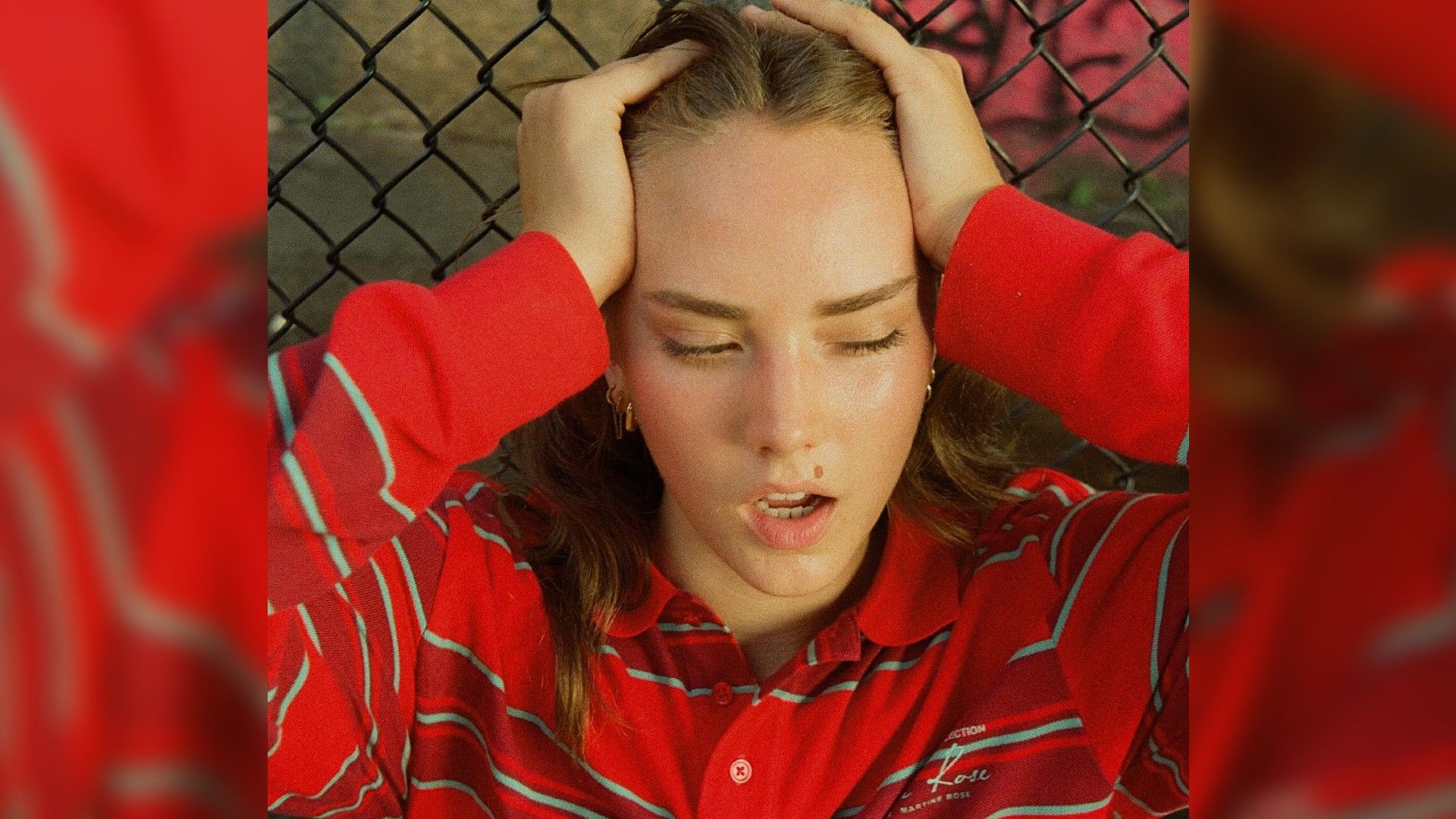 Frances Whitney in a red outfit, face in close-up, hands on her head