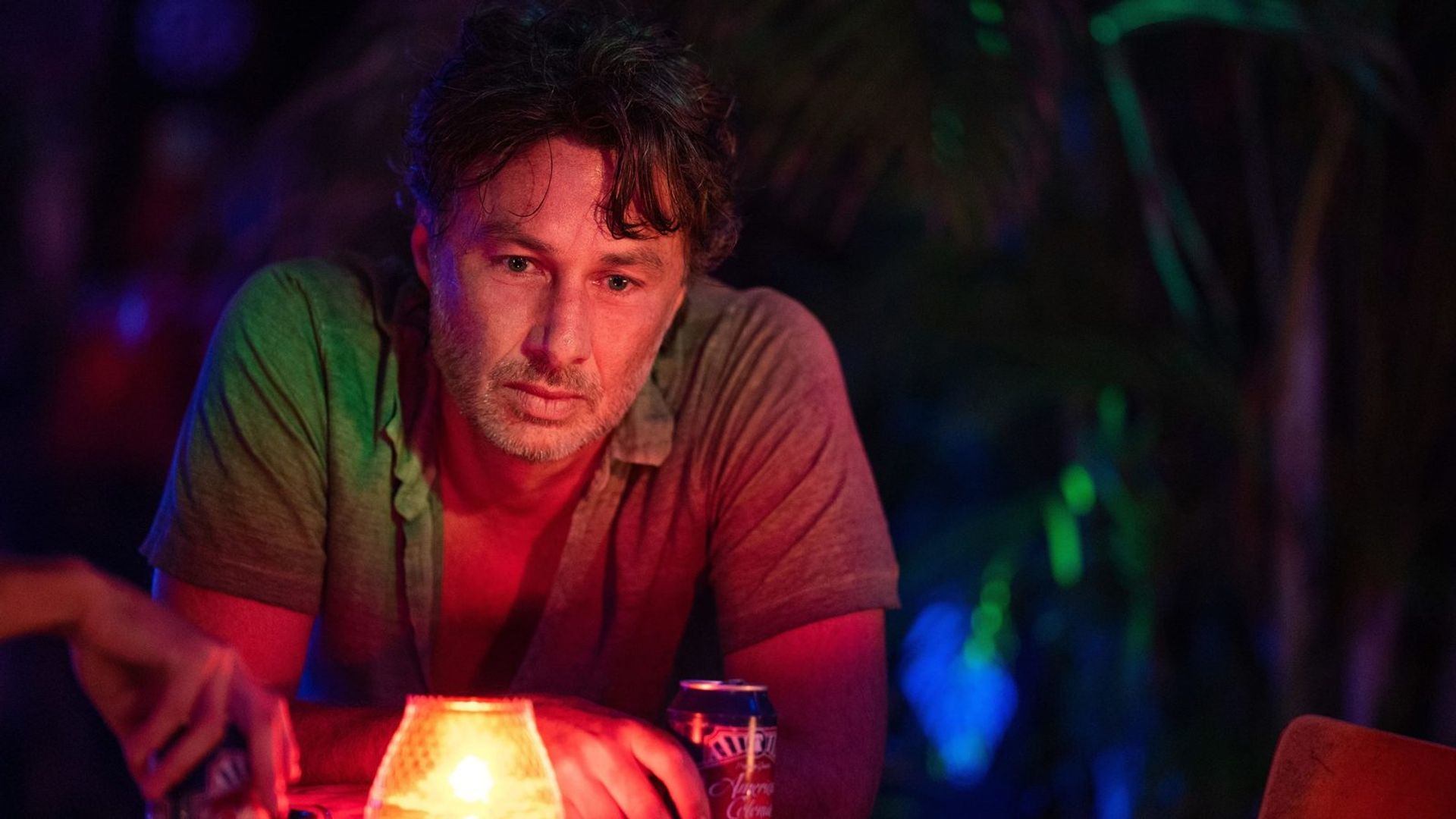 Zach Braff drinks a beverage in neon light