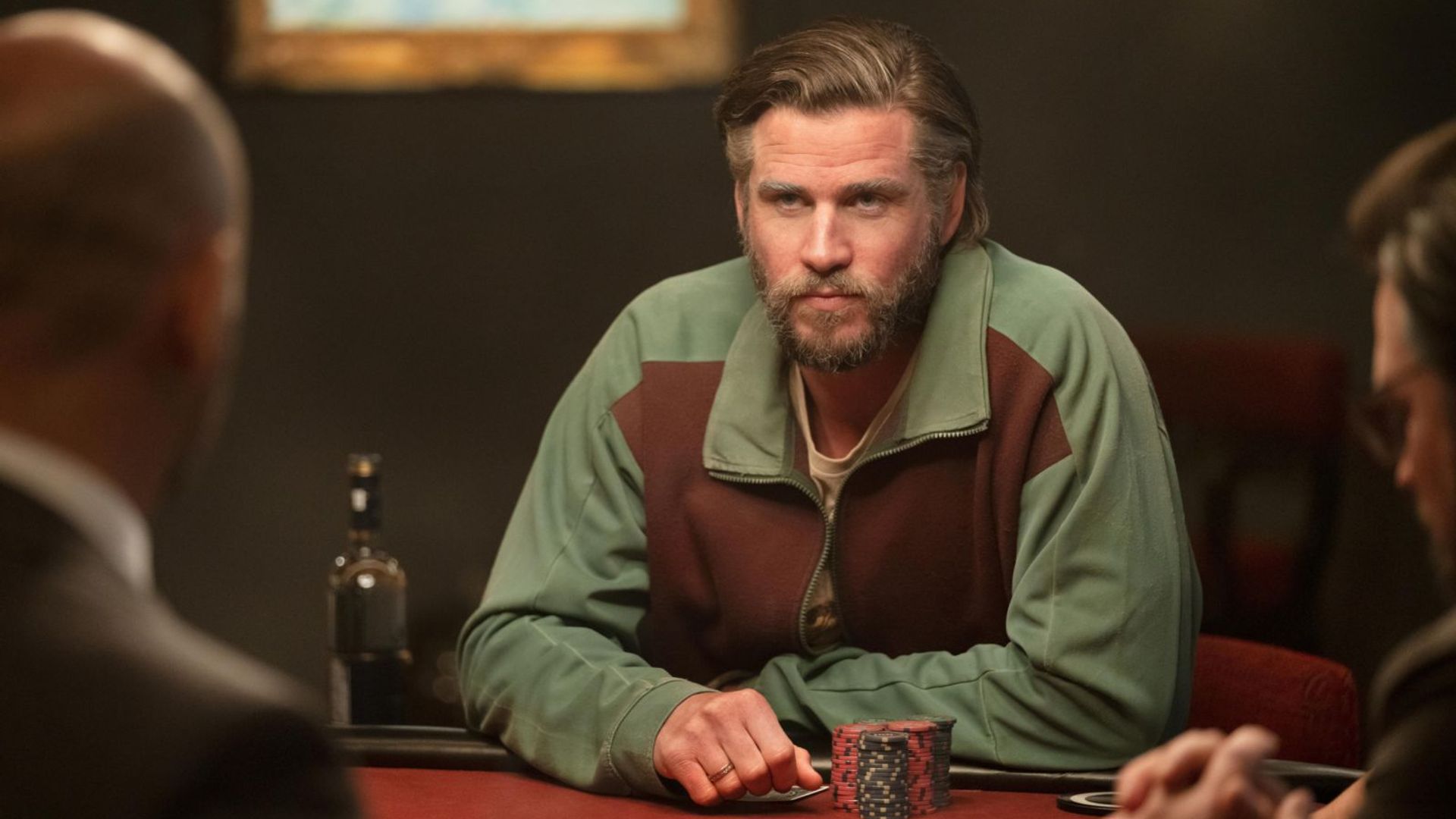 Artificially aged Liam Hemsworth sits at a poker table