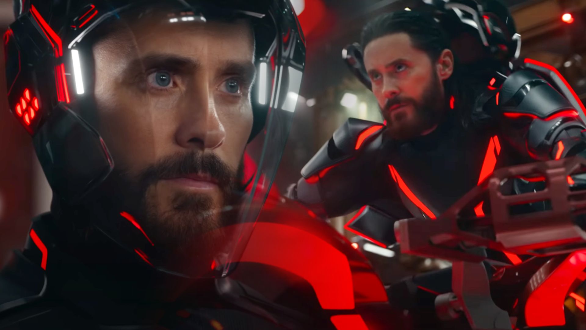 Actor Jared Leto in a futuristic red and black suit riding a motorcycle