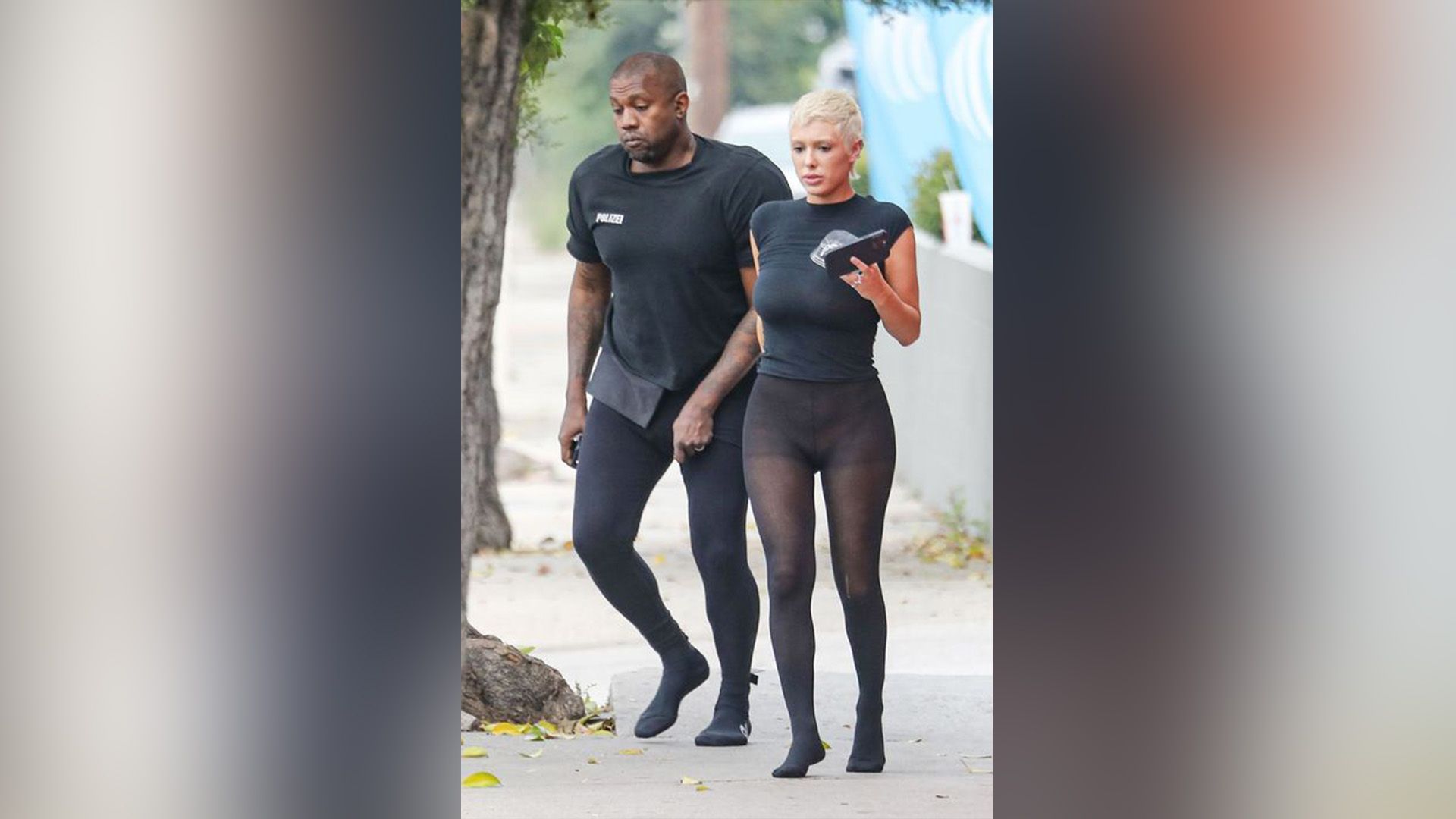 A dark-skinned man in black and a blonde woman in a black T-shirt and black sheer tights