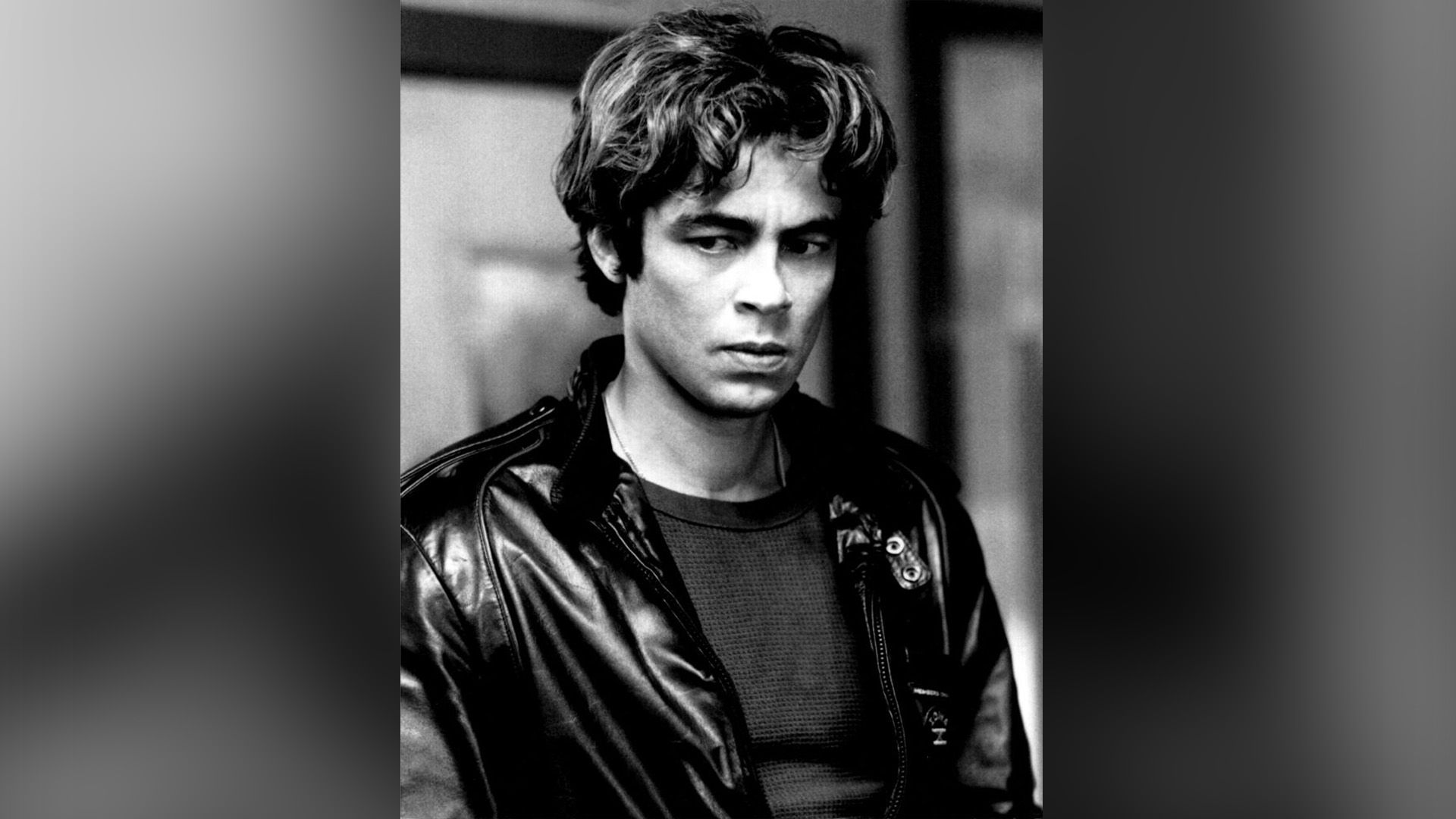 A thoughtful young man with a lush mane, dressed in a black leather jacket