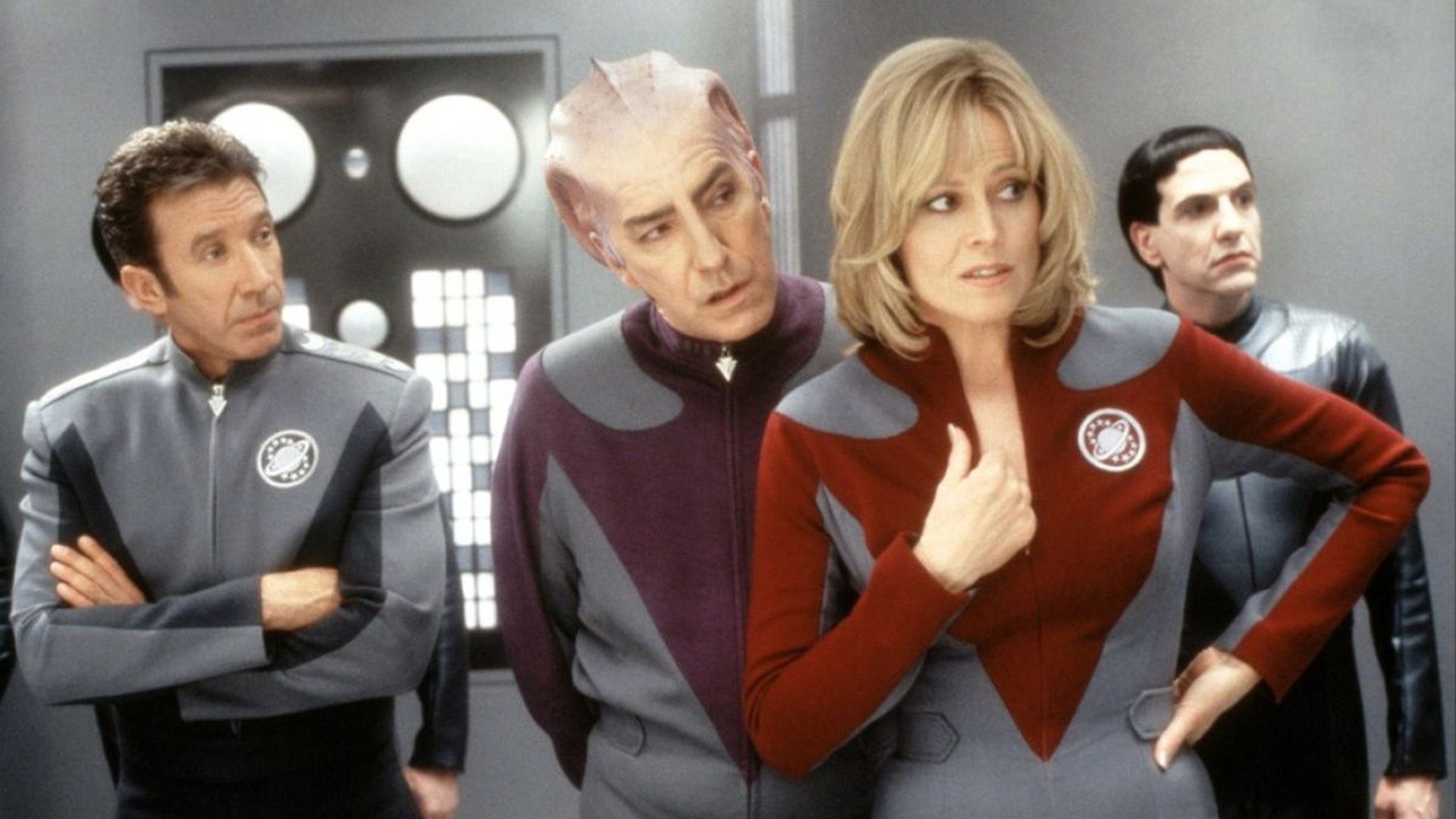 Three men, one of them with an alien appearance, and a woman, all in uniform jumpsuits