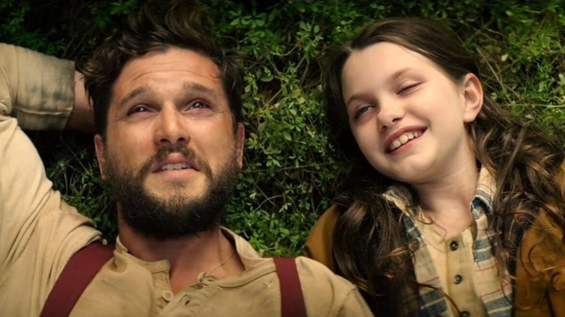A man and a girl are lying on the grass and talking