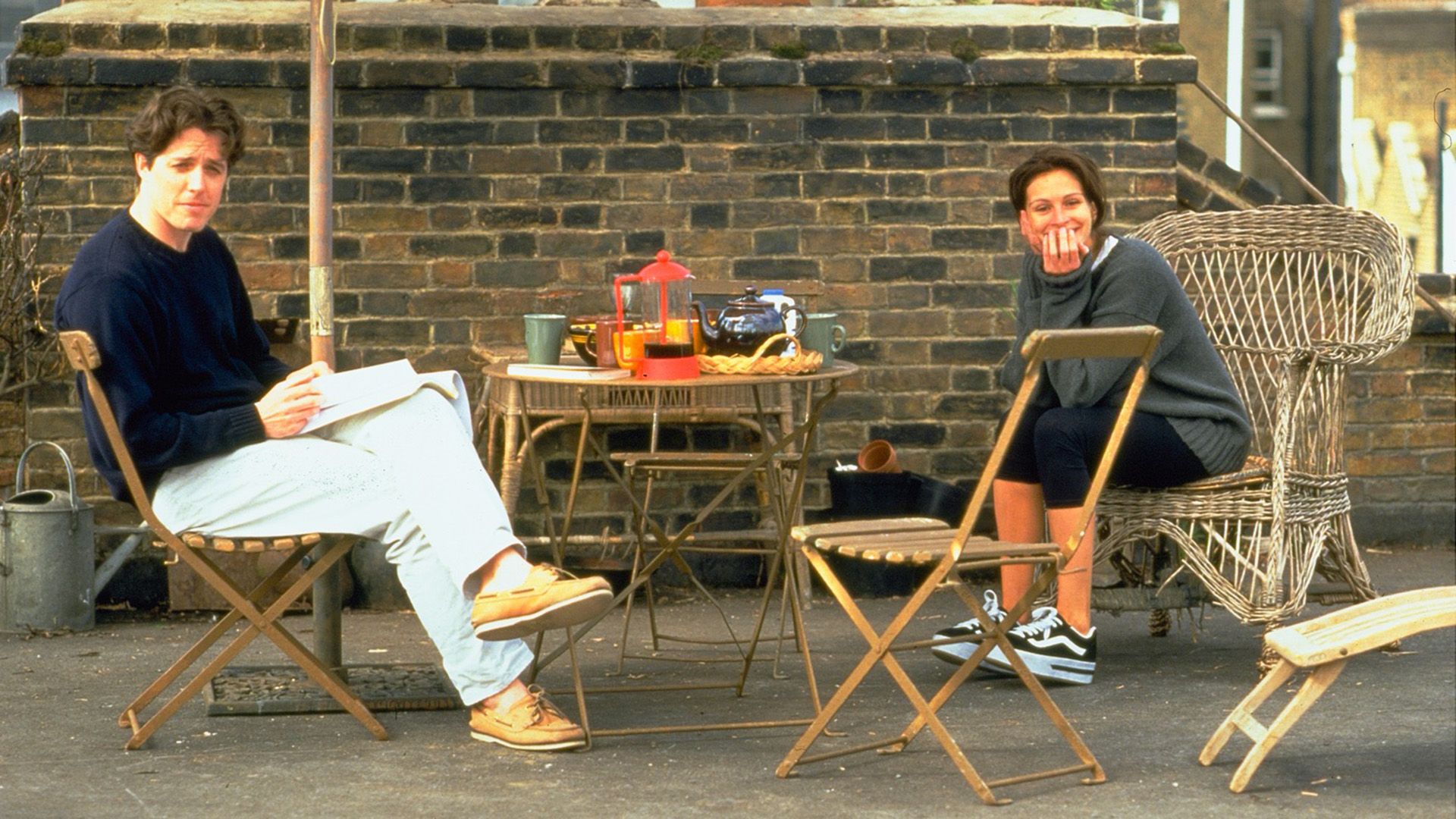 A man and a girl are sitting outside at a coffee table