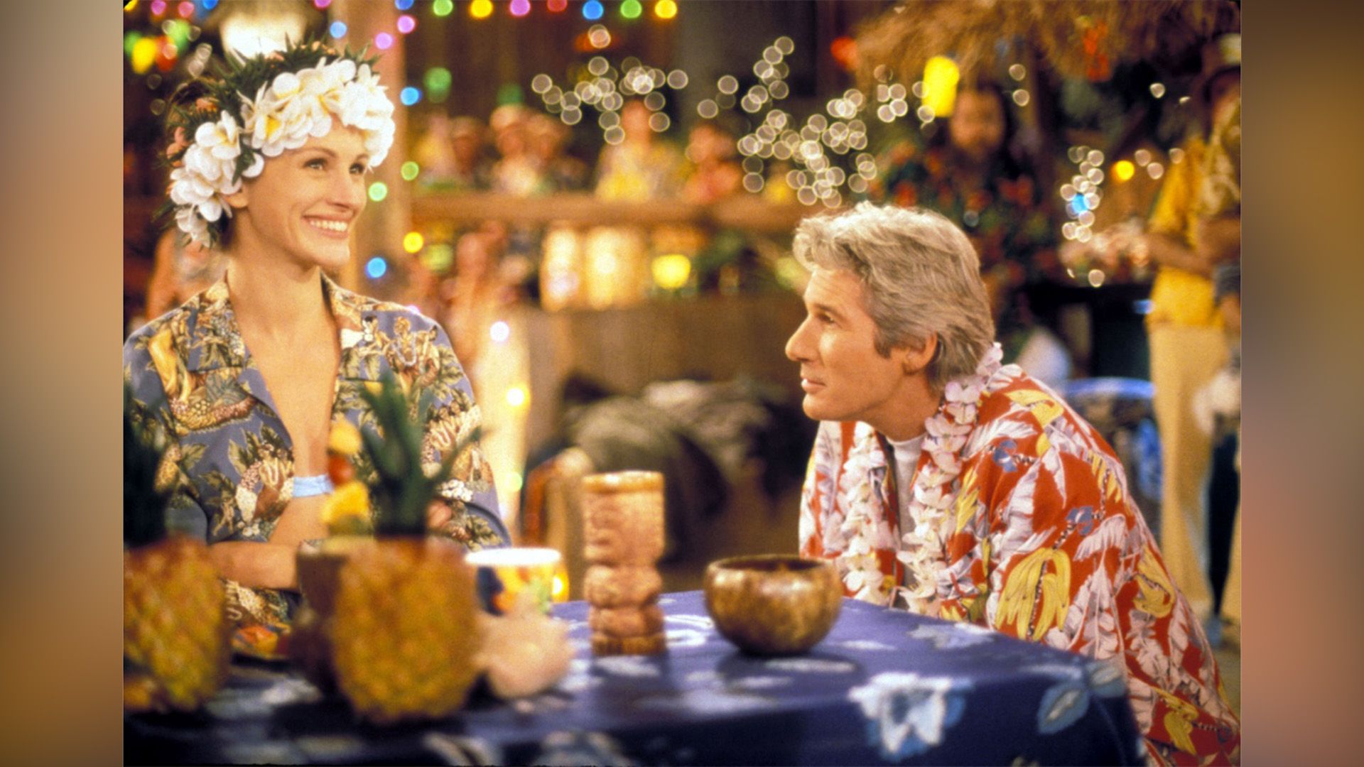 A man and a woman in Hawaiian shirts sitting at a café table