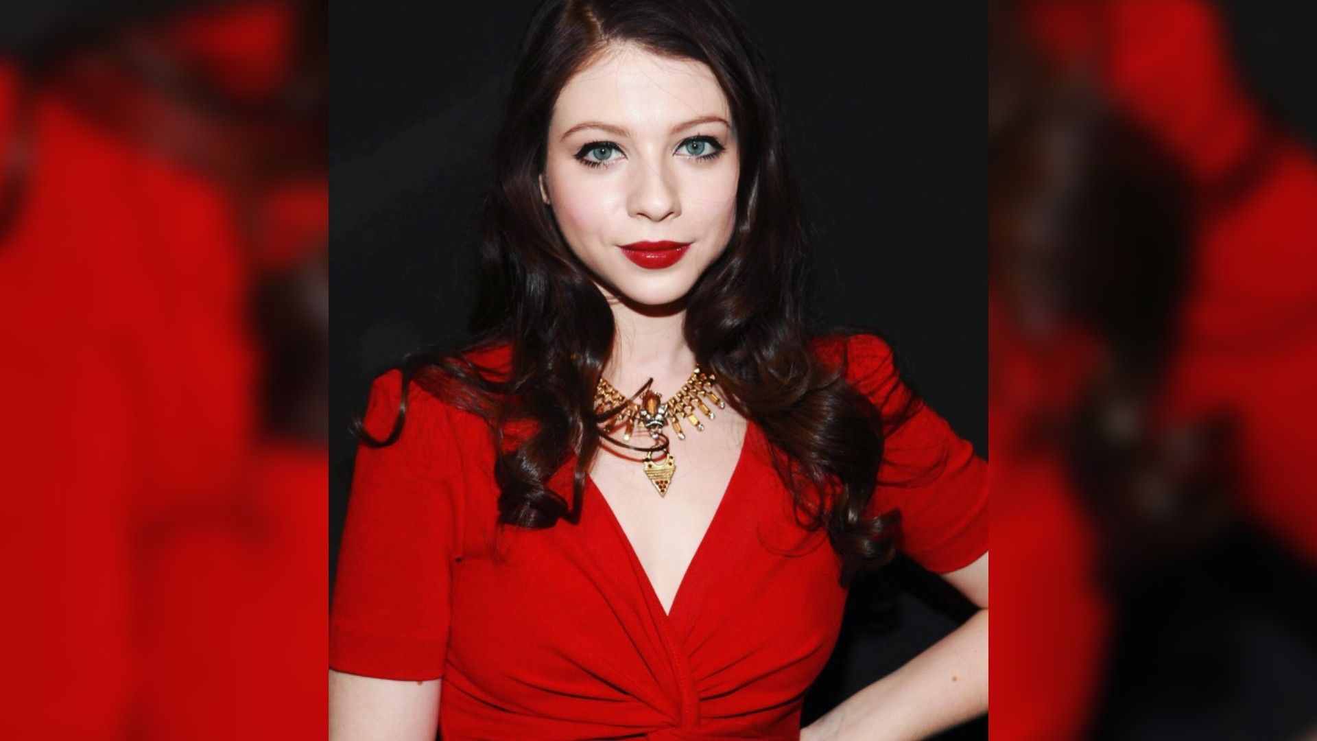 Actress Michelle Trachtenberg in a red dress and bright makeup with red lipstick matching the dress color