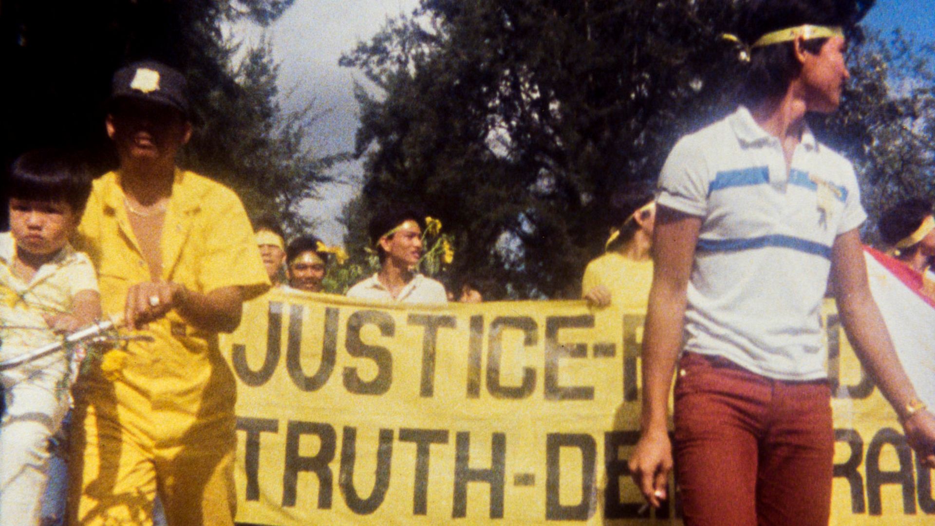 Frame from the film "Why is Yellow the Middle of the Rainbow?": a group of people with a yellow poster at a demonstration