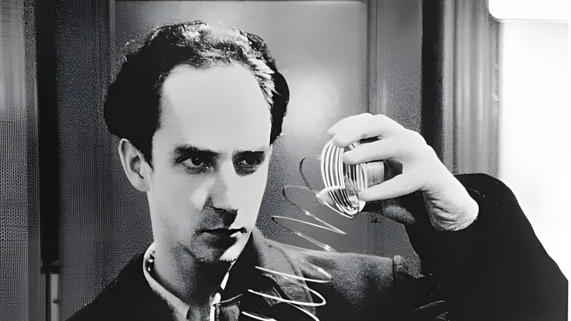 Black-and-white shooting, stylized as vintage. A man holds a slinky toy in his hand