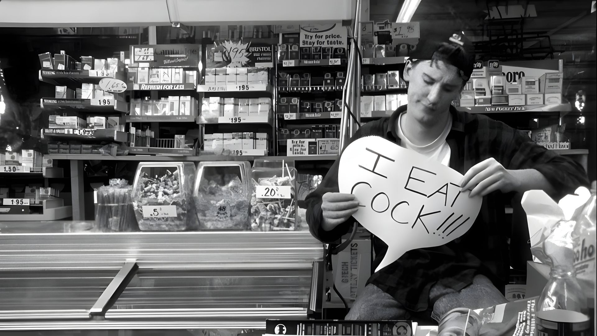 Black-and-white shot, a young man in a cap photographed against the backdrop of the checkout in a supermarket