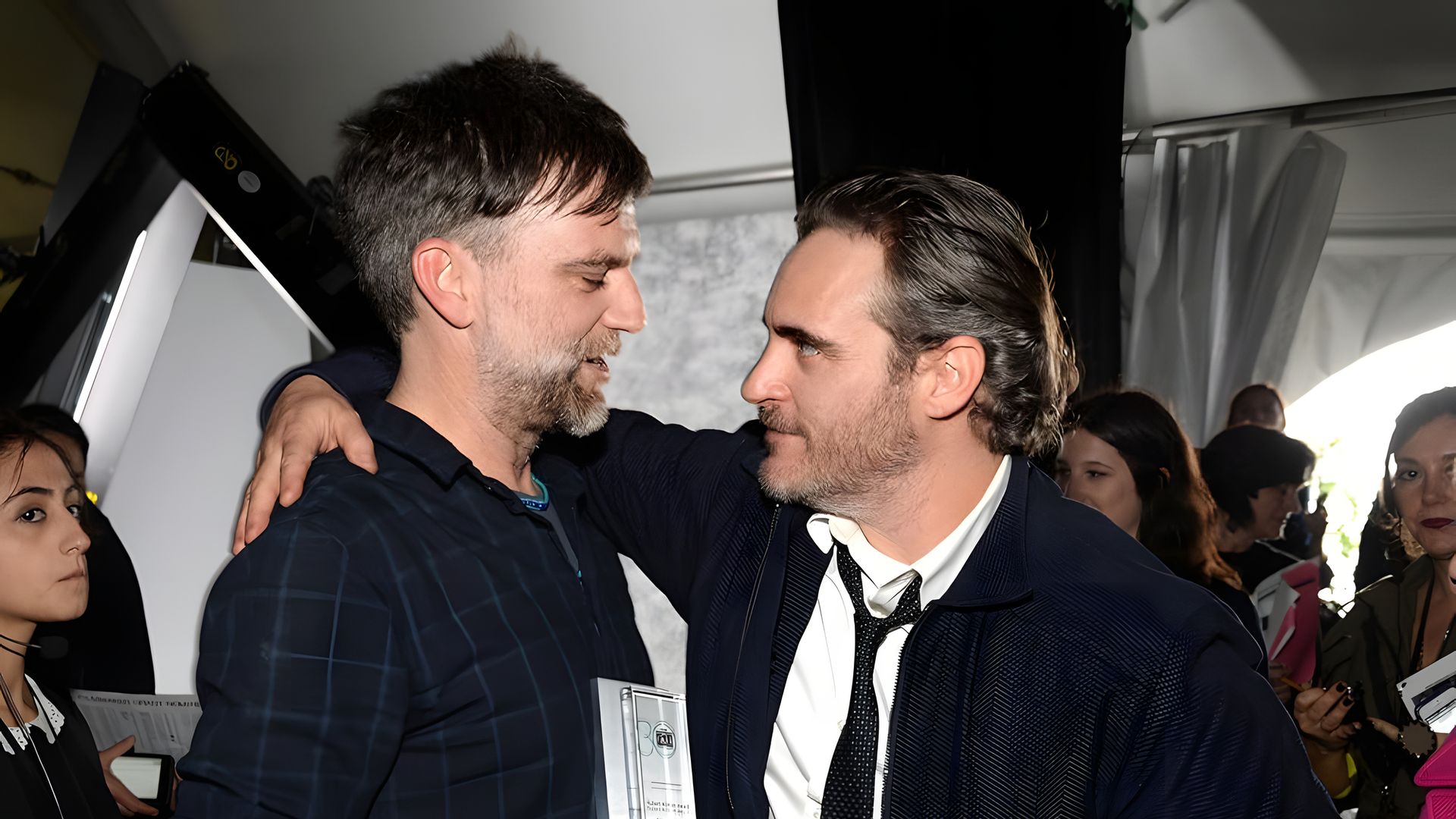 Joaquin Phoenix hugs Paul Thomas Anderson with one hand