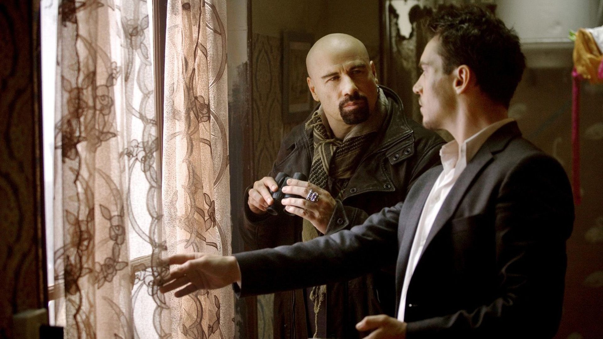 John Travolta and Jonathan Rhys Meyers standing by the window in a scene from the movie 'From Paris with Love'