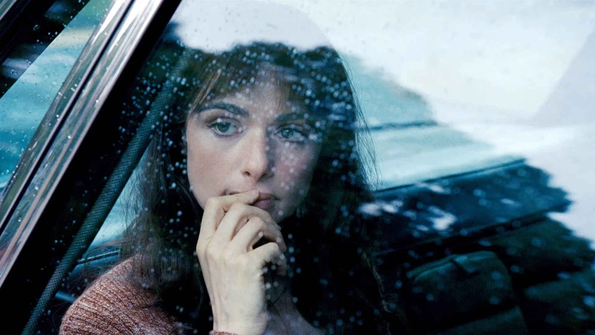 Close-up of actress Rachel Weisz's face shot through car glass in the rain