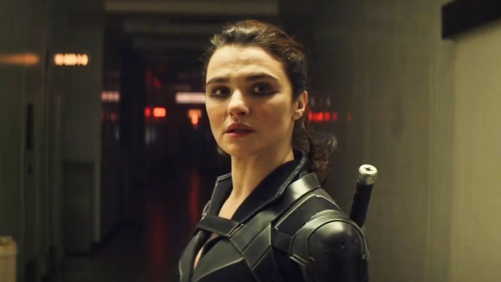 Actress Rachel Weisz with her hair tied back in a ponytail, wearing a black superhero costume