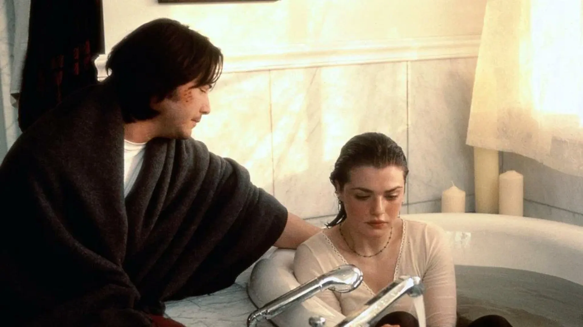 Young Rachel Weisz is sitting in the bathtub in her clothes, next to her sits young Keanu Reeves