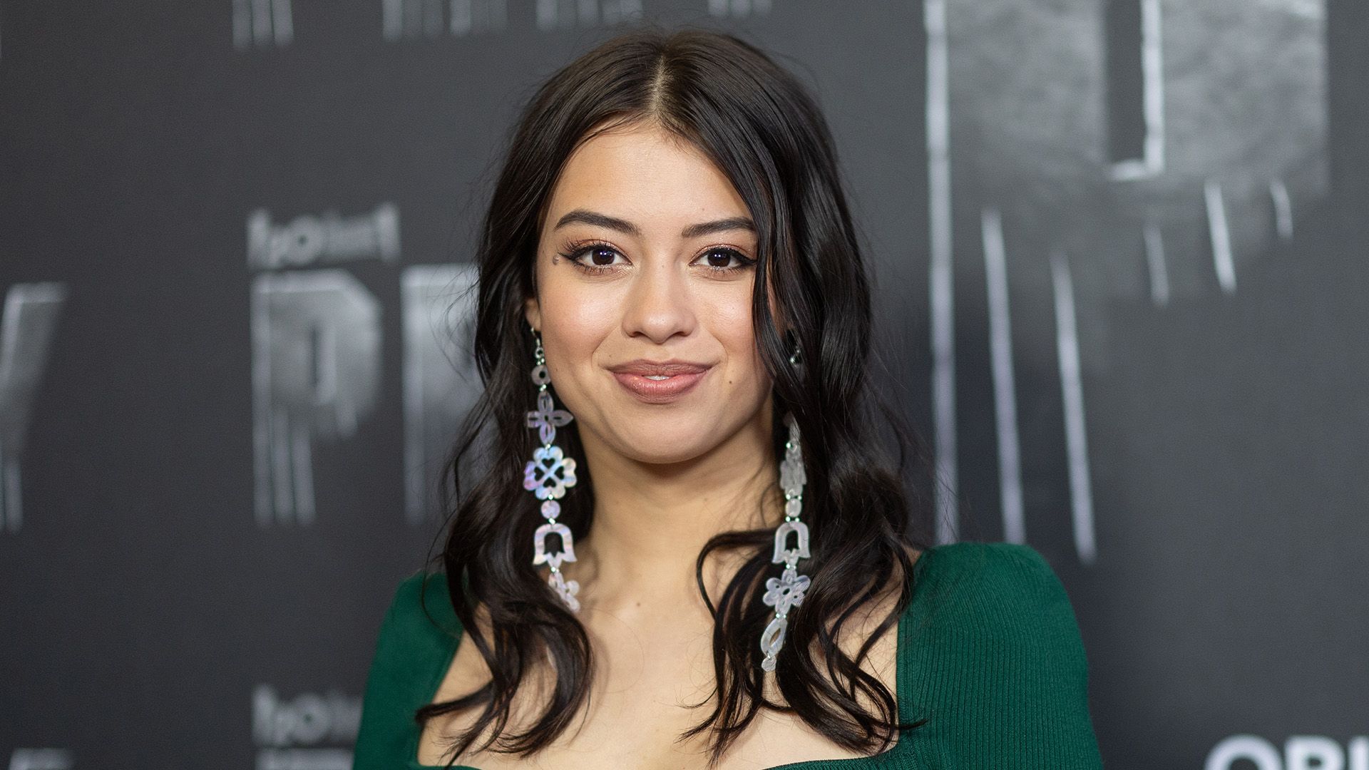 Actress Amber Midthunder in a green dress against a gray background