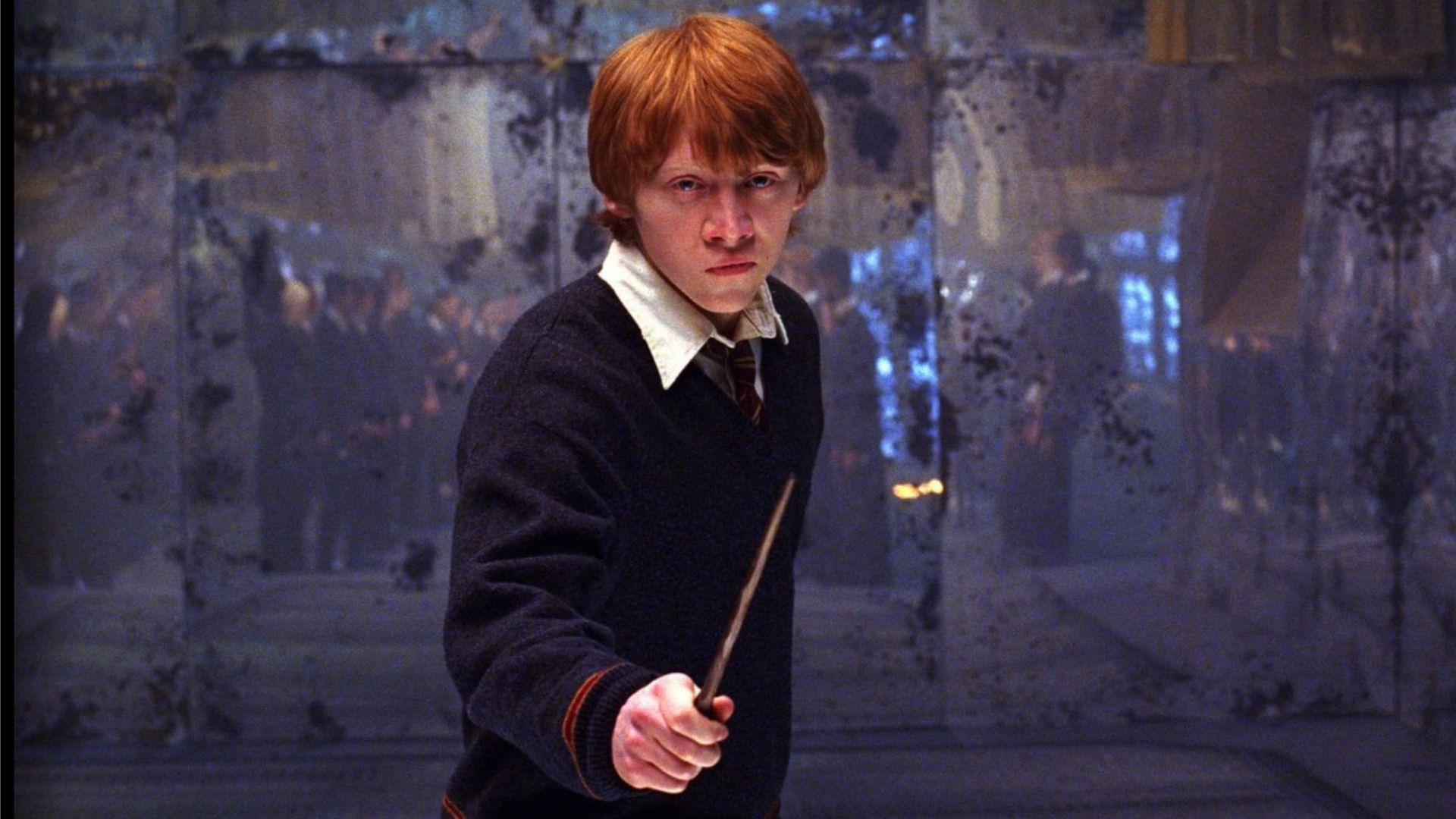 Actor Rupert Grint in his youth as Ron Weasley, standing with a wand in front of a mirror