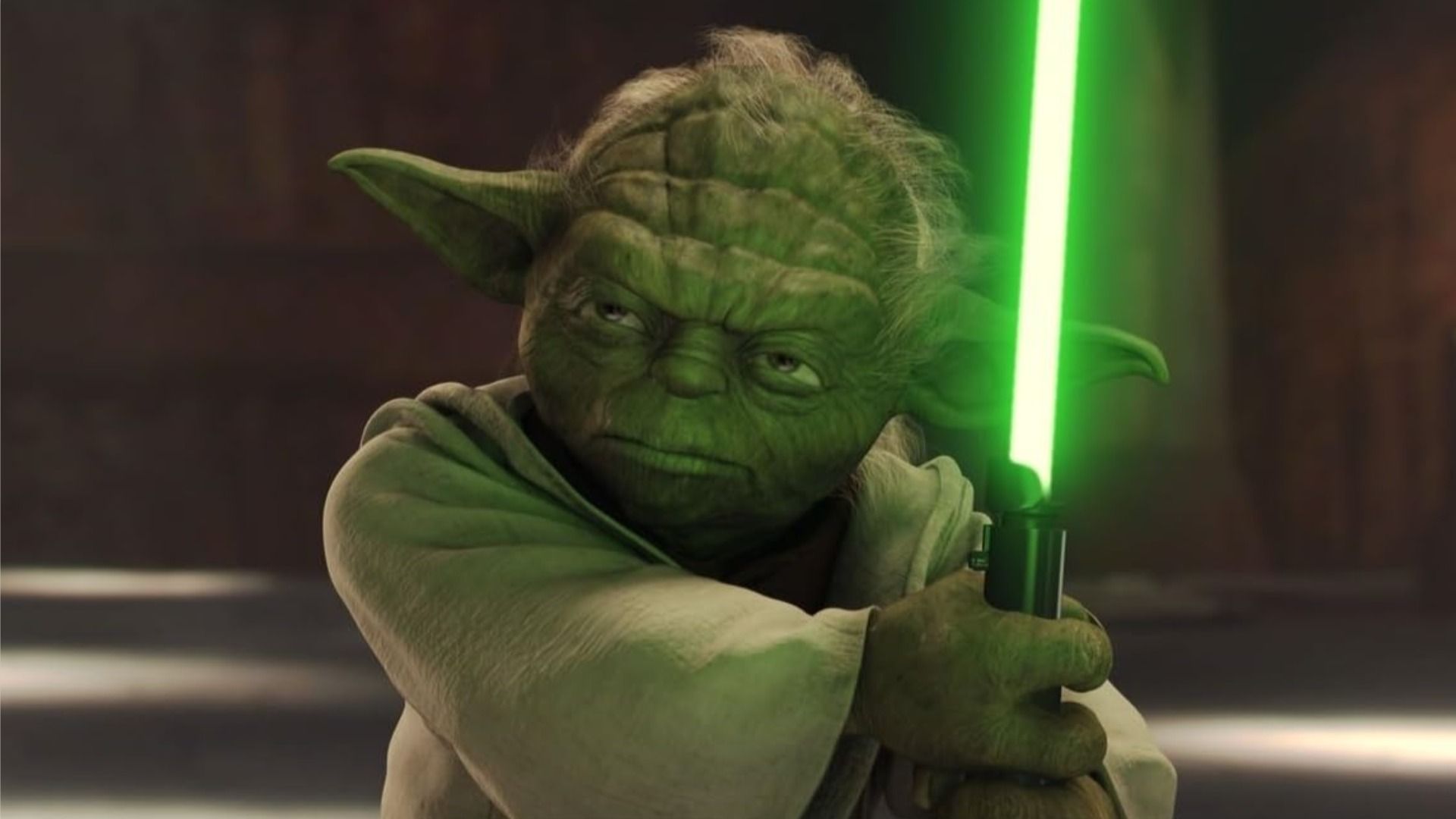 Master Yoda holds a lightsaber and looks sternly to the side against a brown background