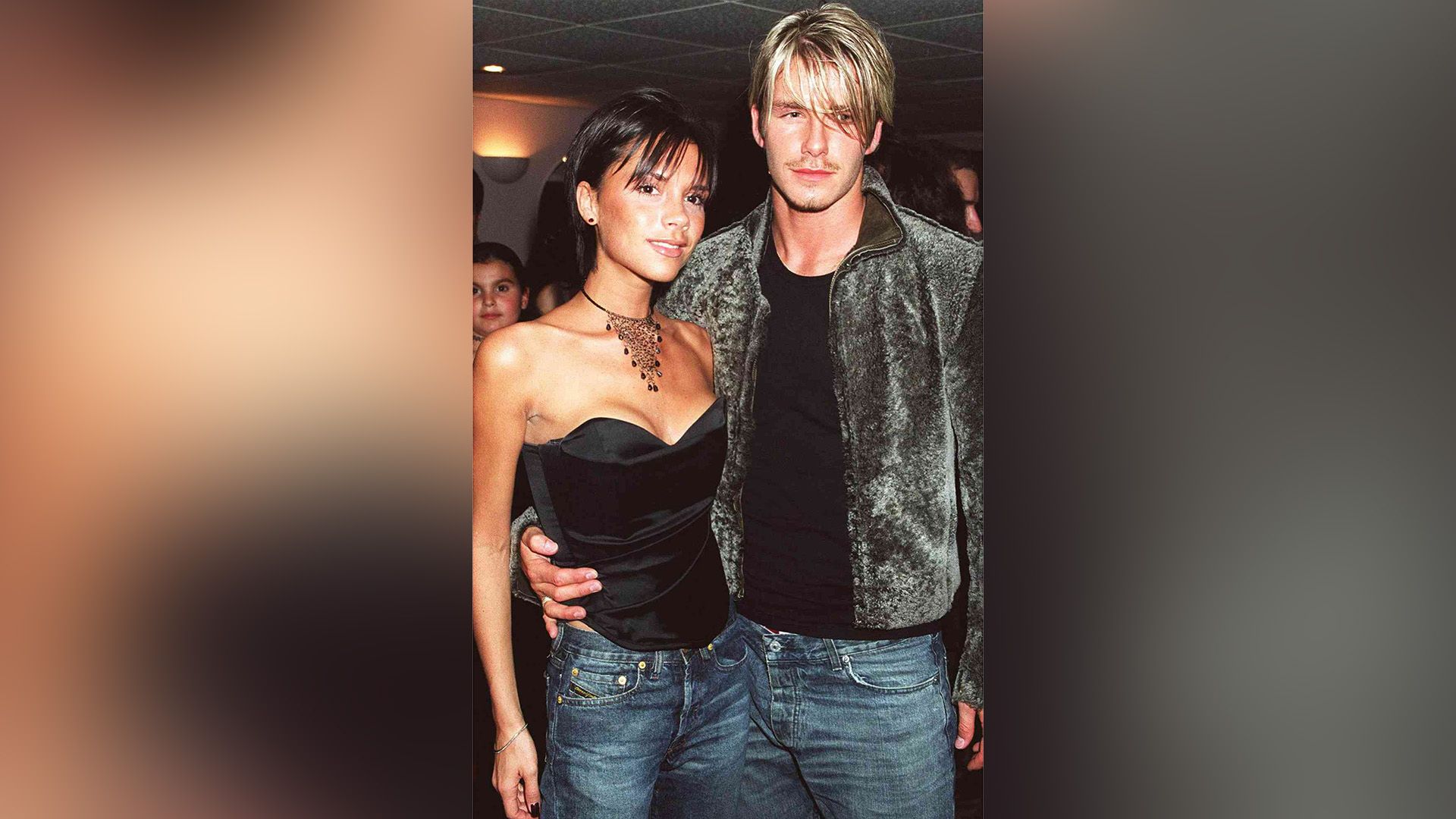 Young David Beckham hugs Victoria Adams by the waist at a social event